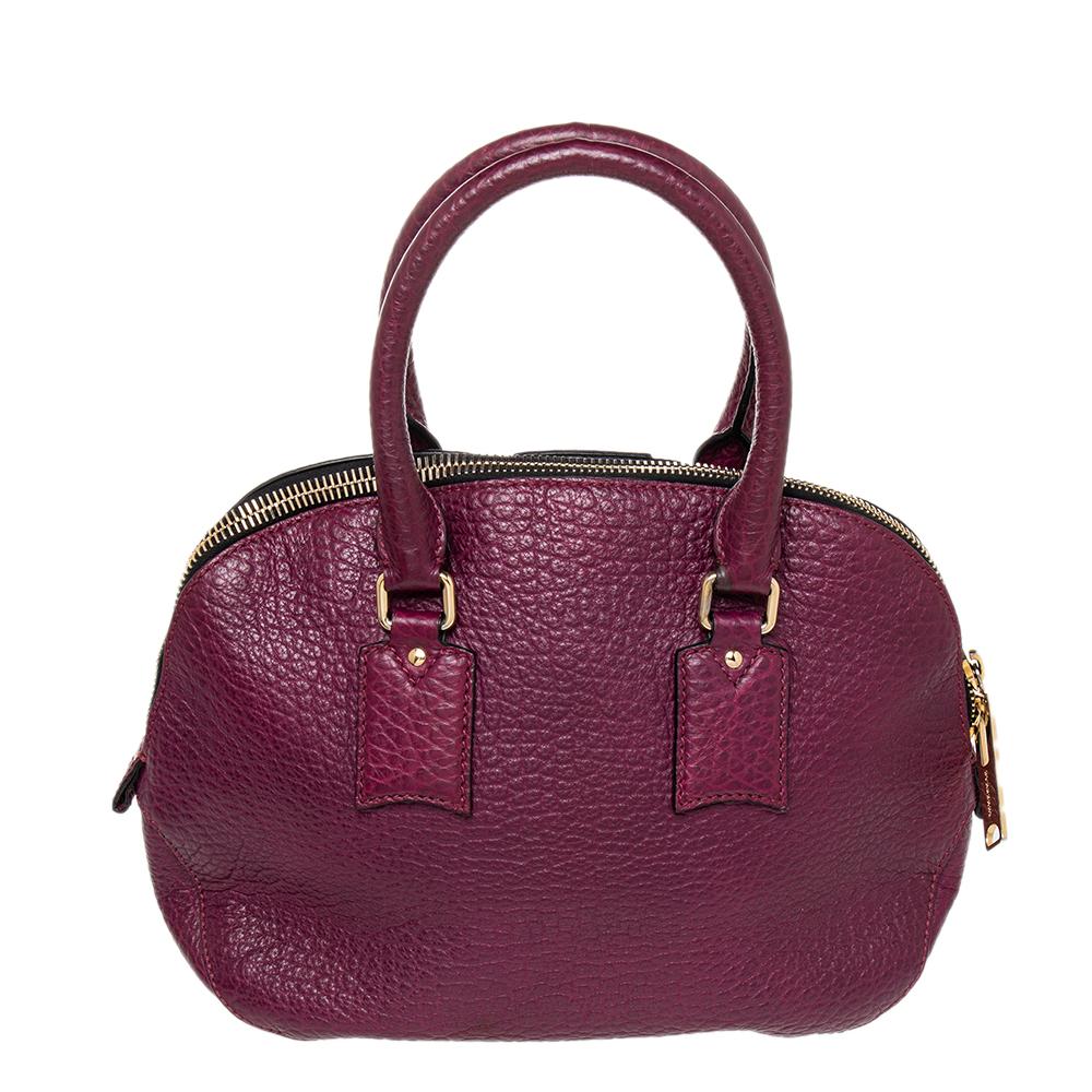 Look super stylish with this Burberry Orchard Bowling bag. This cute bowling-style bag is crafted of richly textured leather in burgundy. The bag features rolled leather top handles, a detachable strap, a clochette dangling from the handle, and a