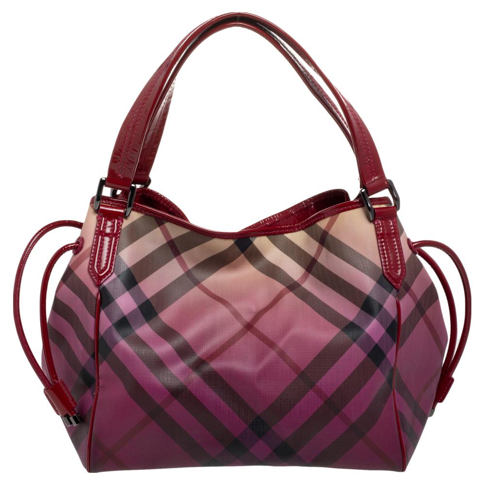 You are definitely going to catch a lot of admiring glances as you flaunt this Bilmore tote by Burberry. It has been crafted from PVC in their signature Supernova check and enhanced with patent leather. The bag features a spacious canvas interior