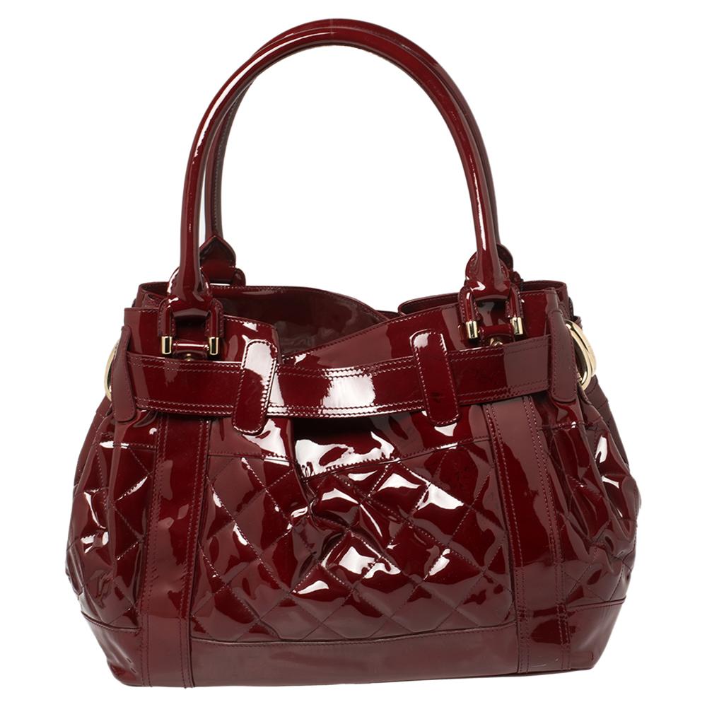 Carry all your essentials stylishly in this fabulous Burberry Beaton bag crafted in patent leather. This bag is highlighted with the quilts, a belt buckle closure, and gold-tone hardware. It comes with double-rolled top leather handles. The