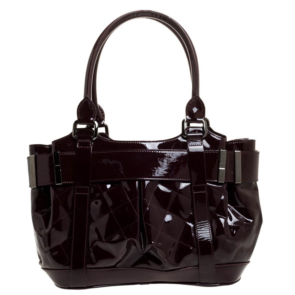 Diese exquisite Handtasche von Burberry ist von unvergleichlicher Schönheit. Diese Healy-Tasche aus Lackleder mit zwei Henkeln und Gürteldetails auf der Vorderseite ist ein praktisches Accessoire für unterwegs. Der mit Stoff gefütterte Innenraum ist