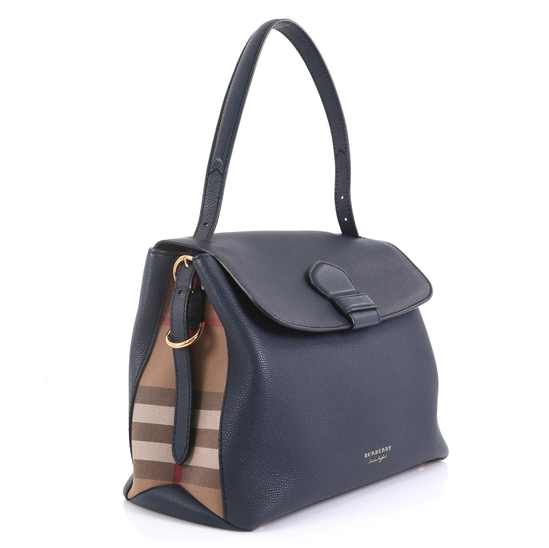 This Burberry Camberley Top Handle Bag Leather Medium, crafted in blue leather, features a flat leather handle, flap top, and gold-tone hardware. Its magnetic snap button closure opens to a blue fabric interior divided into two open compartments