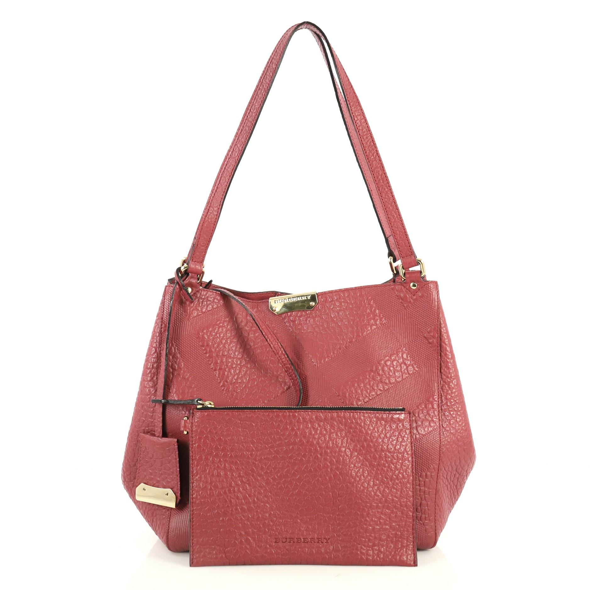 This Burberry Canterbury Tote Check Embossed Leather Small, crafted from pink check embossed leather, features dual flat leather shoulder straps, protective base studs, and gold-tone hardware. Its magnetic snap closure opens to a pink leather