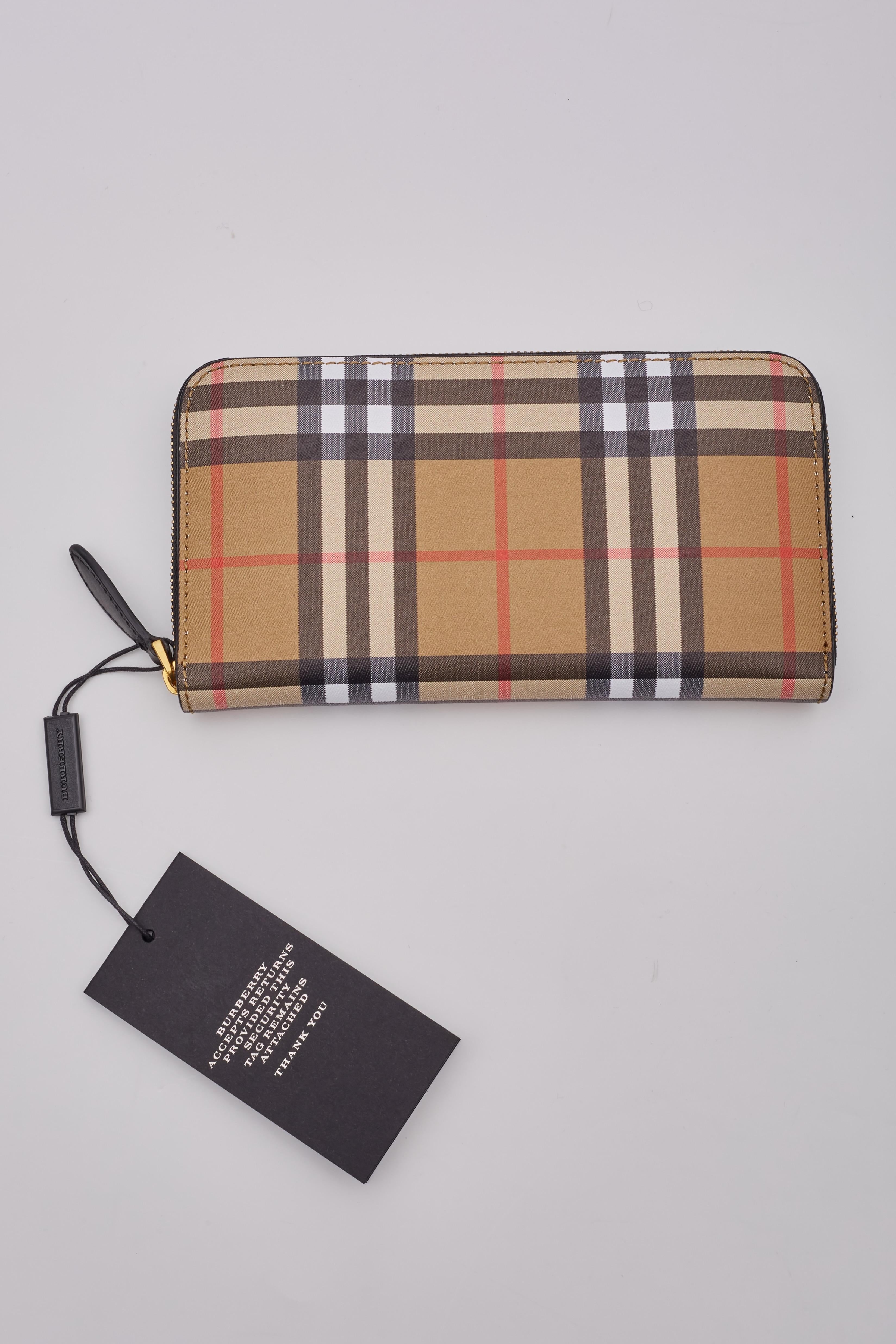 This wallet is made of leather with Burberry check print and has a 3/4 wrap around brass zipper that opens to a black leather interior lined with card slots, flat pockets, and a central zipper pocket.

Color: Beige Burberry check
Material: