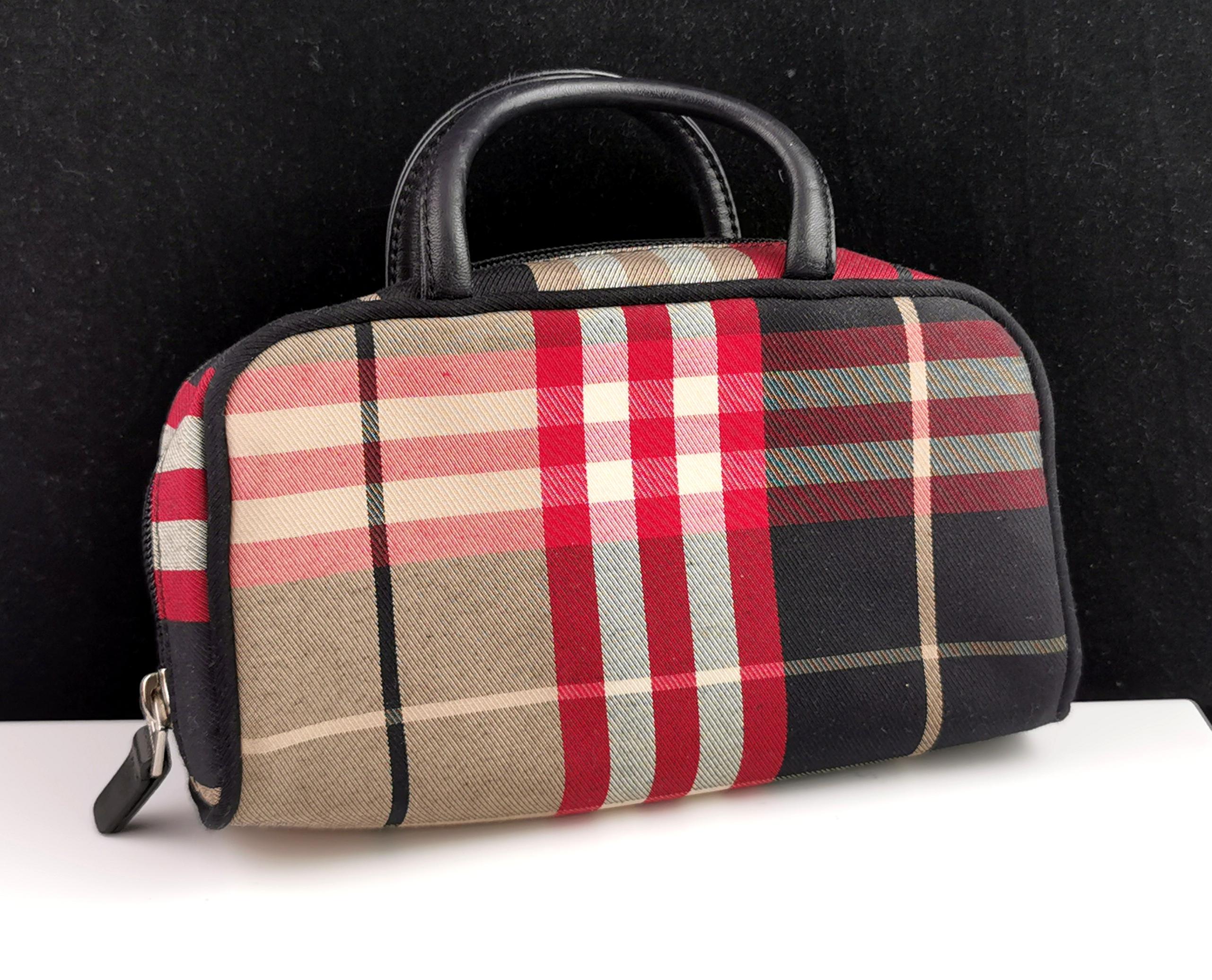 A stylish Burberry mini bowling bag.

It is a very small bag, a cosmetics or toiletries bag in the new style check with black faux leather top handles.

It has a zip fastener with a branded zip and label inside for Burberry London.

Inside there are