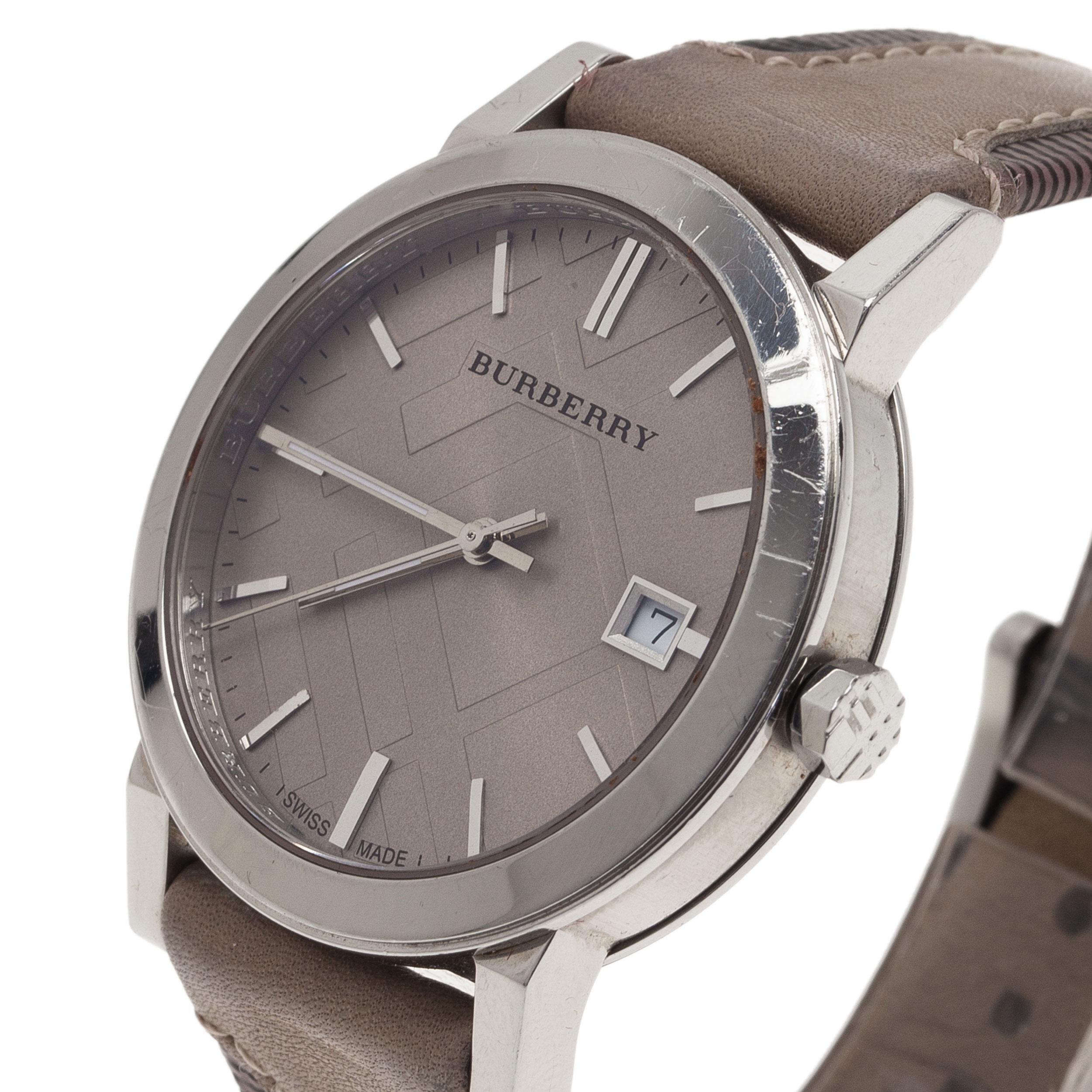 This Burberry Haymarket wristwatch comes crafted in stainless steel. The rounded case holds a bezel housing a dial embossed with check. It features silver-tone hour index bars, slim hands and a date window at 3 o'clock. It comes with a leather