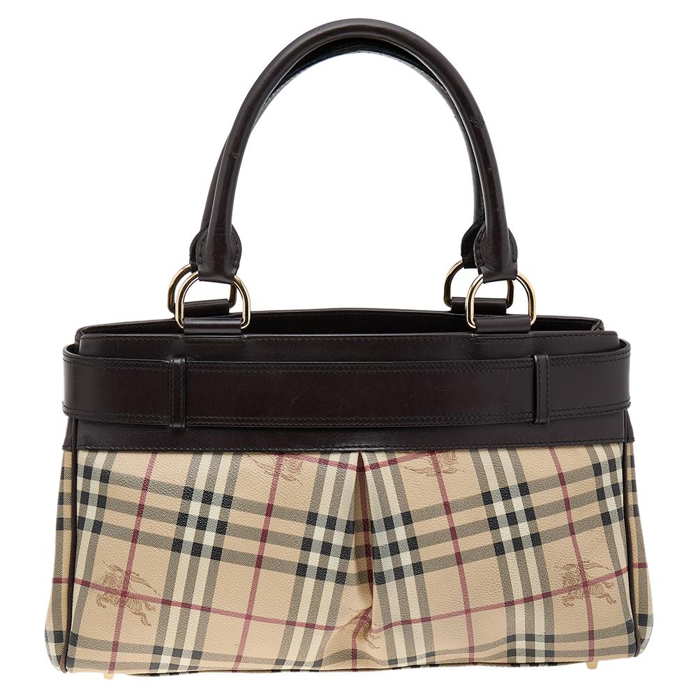 Adorned with the classic Burberry Haymarket check canvas, this Burberry Bridle tote is accented with dark brown leather. It is detailed with a huge buckled belt on the front and rolled leather top handles. The open-top leads to a canvas-lined