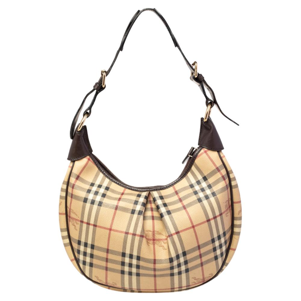 A fine blend of style and elegance, this Burberry hobo will instantly elevate any simple look. It is crafted from the signature Nova Check coated canvas and is styled with leather trims. The Barton hobo comes with a single handle and a spacious