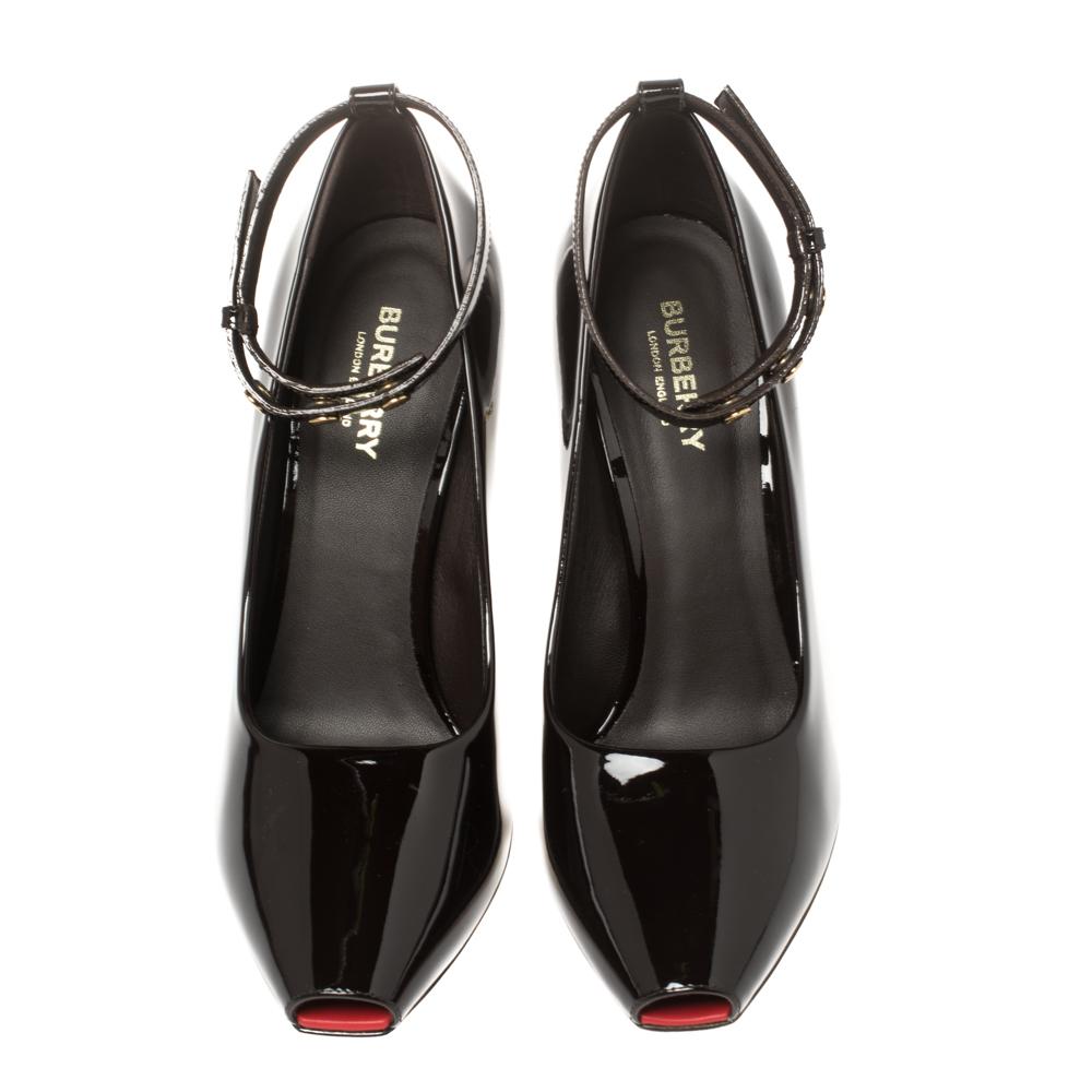 Los zapatos de salón Jermyn de Burrbery definen el encanto elegante y la estética minimalista de la marca. Están hábilmente confeccionados en charol en un tono marrón oscuro y se caracterizan por sus cortes lujosos, detalles únicos y una