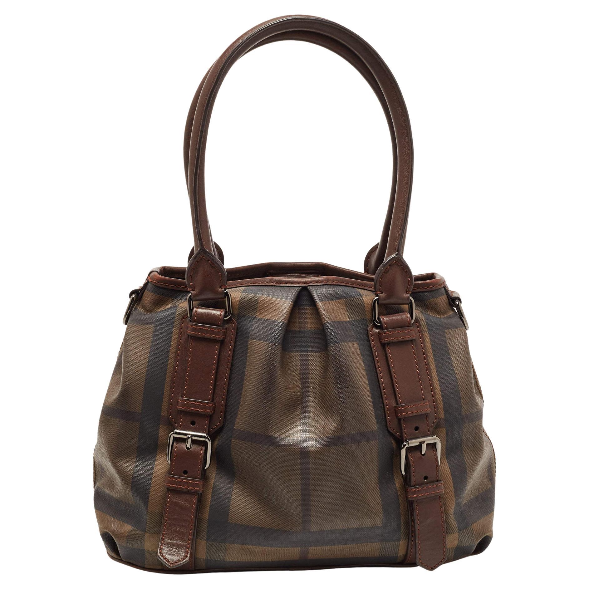This Northfield tote from Burberry is crafted from signature Smoke check coated canvas and leather. It is equipped with two rolled handles, a detachable shoulder strap, and a well-sized canvas interior to house your belongings. The dark brown shade