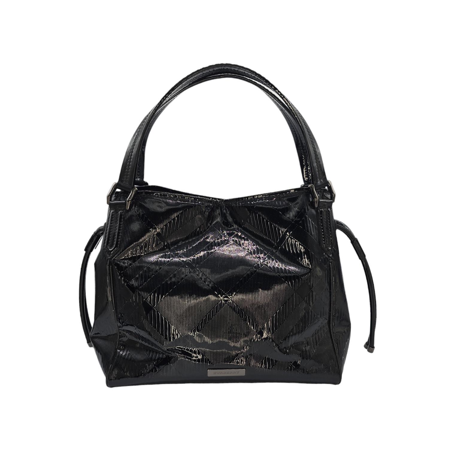 Offrez-vous le luxe avec le fourre-tout Bilmore en vernis gaufré de Burberry. Ce fourre-tout chic est confectionné en cuir verni à carreaux de couleur noire. Le sac est doté de bandoulières en cuir Looping avec des ferrures en ruthénium poli, et de