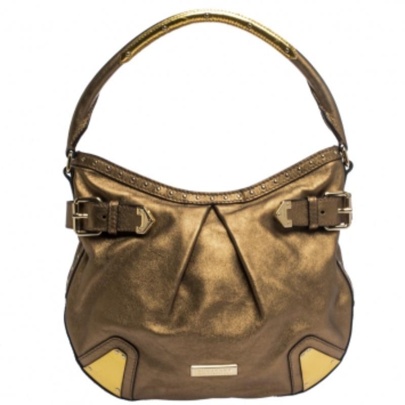 Displaying perfect designs, this Burberry hobo bag is a closet staple and stands out. Crafted from quality leather, it comes in a lovely shade of gold. It has a slouchy silhouette, single handle, stud & buckle detailing, brand log in the front and