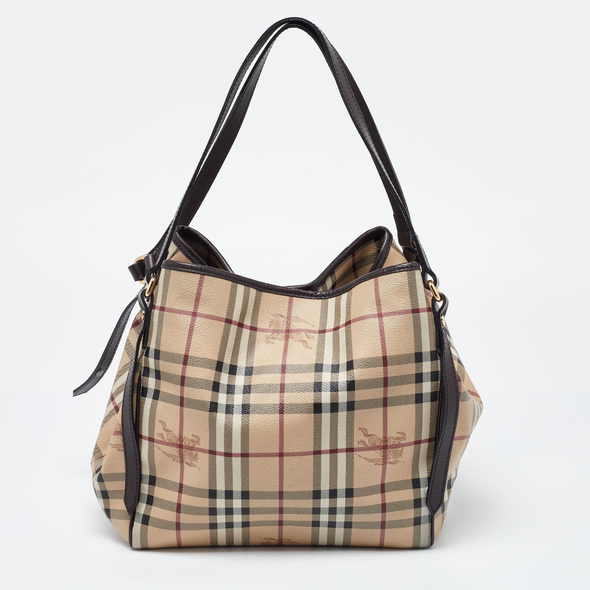 The Canterbury tote from Burberry will suffice your handbag needs with complete elegance. This tote is designed using beige-brown Haymarket Check coated canvas, leather, and gold-tone hardware. It is supported by dual handles and comes with a