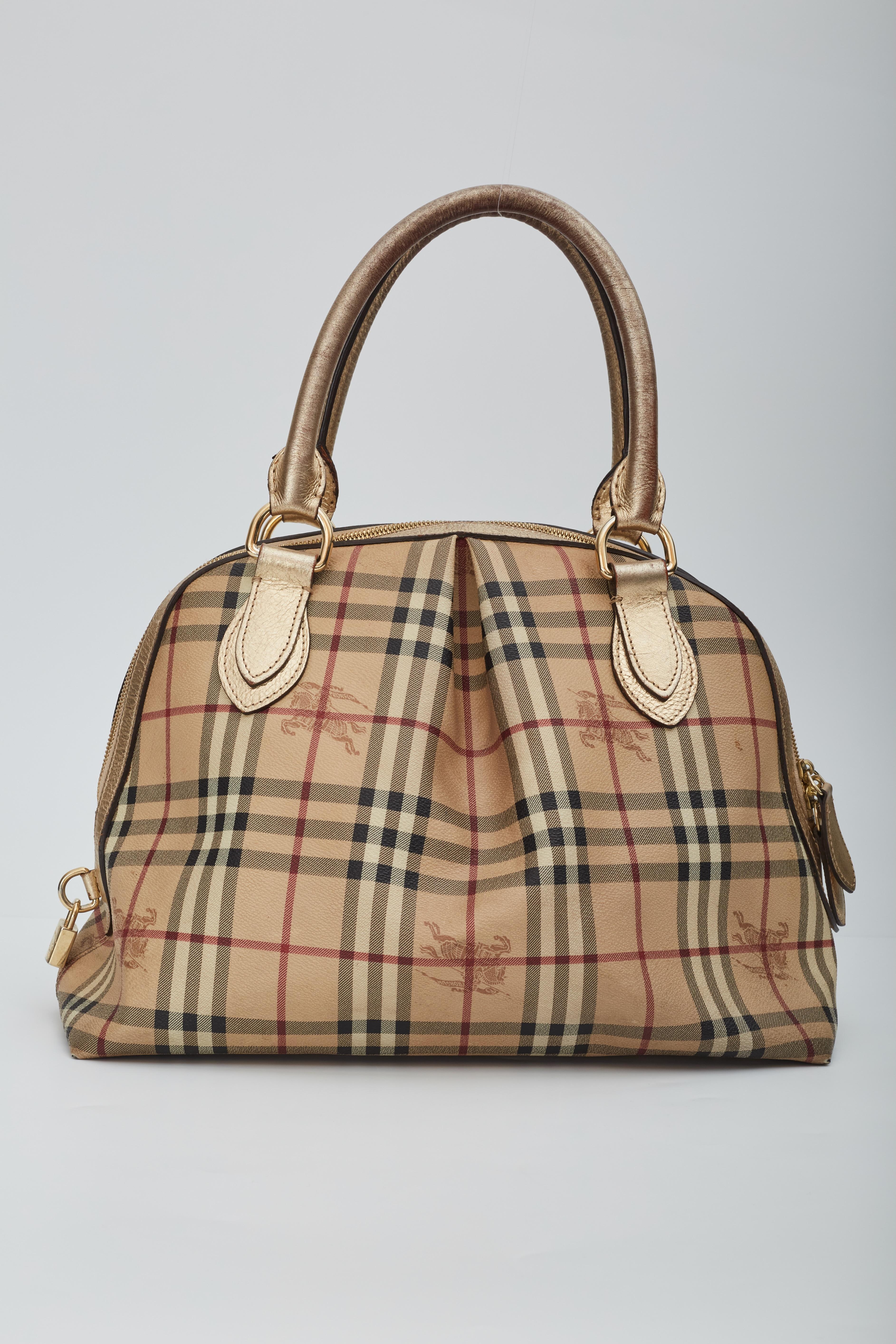 Burberry Top Handle Bag. Haymarket Check Pattern. Gold-Tone Hardware. Leather Trim. Coated Canvas Exterior. Dual Rolled Leather top Handles. Leather Trim Embellishment. Canvas Lining & Three Interior Pockets. Zip Closure at Top. Protective Feet at