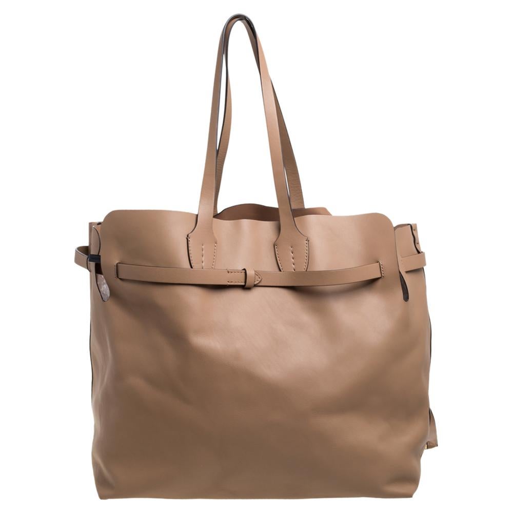 This tote by Burberry has fashion and functionality all rolled into one! Crafted in light caramel leather, the bag comes with dual top handles. Designed with a buckled belt detail at the exterior, the bag opens to a leather-lined interior featuring