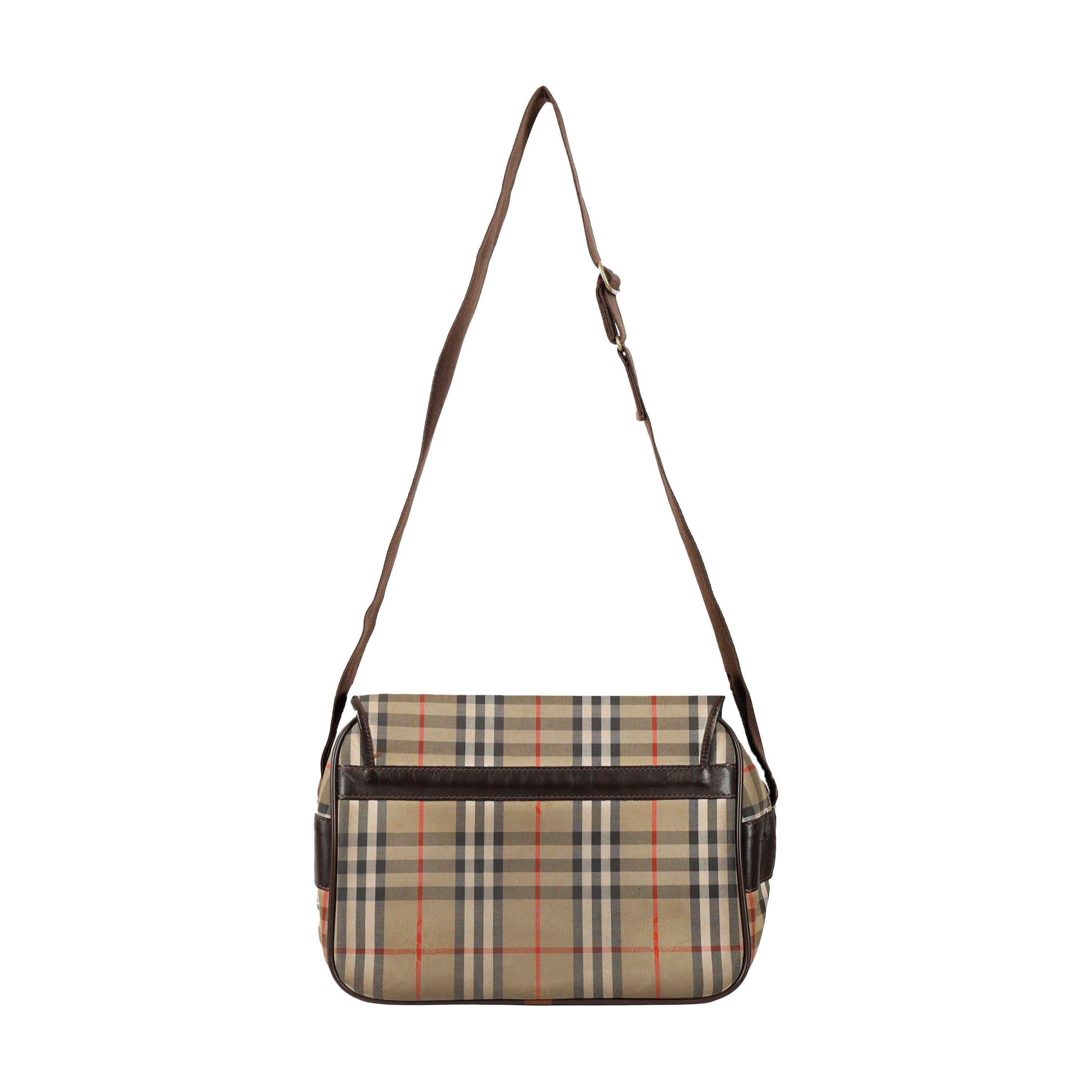 Doté des carreaux emblématiques de Burberry et d'une finition ton olive, il est agrémenté de finitions et de détails en cuir marron foncé contrastant. Ses multiples compartiments et poches zippées offrent une grande capacité de rangement et une