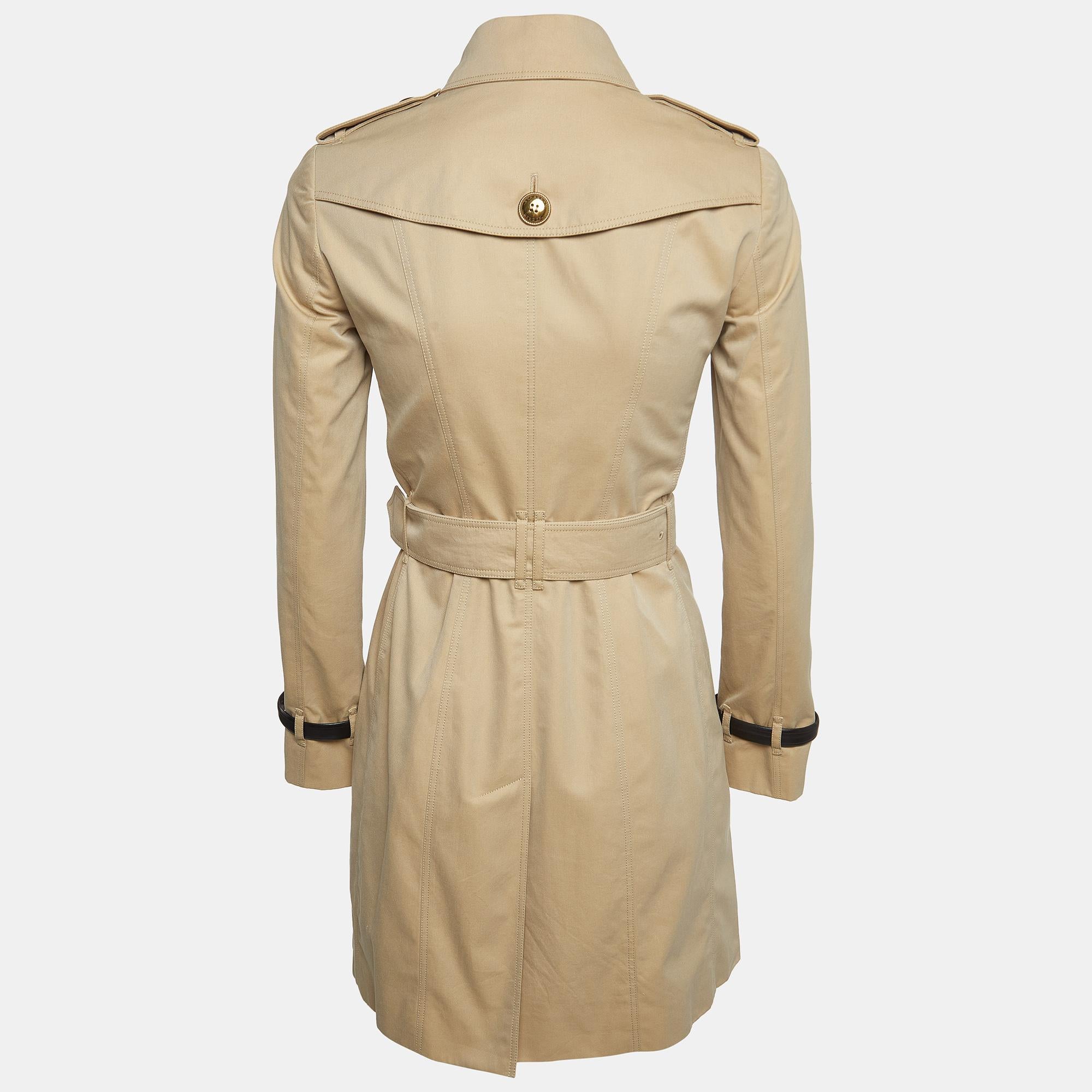 Crafted in Burberry's iconic beige gabardine, this trench coat exudes timeless elegance. Its belted silhouette cinches at the waist, flattering the figure, while classic details like epaulettes and a storm flap nod to traditional design. Practical