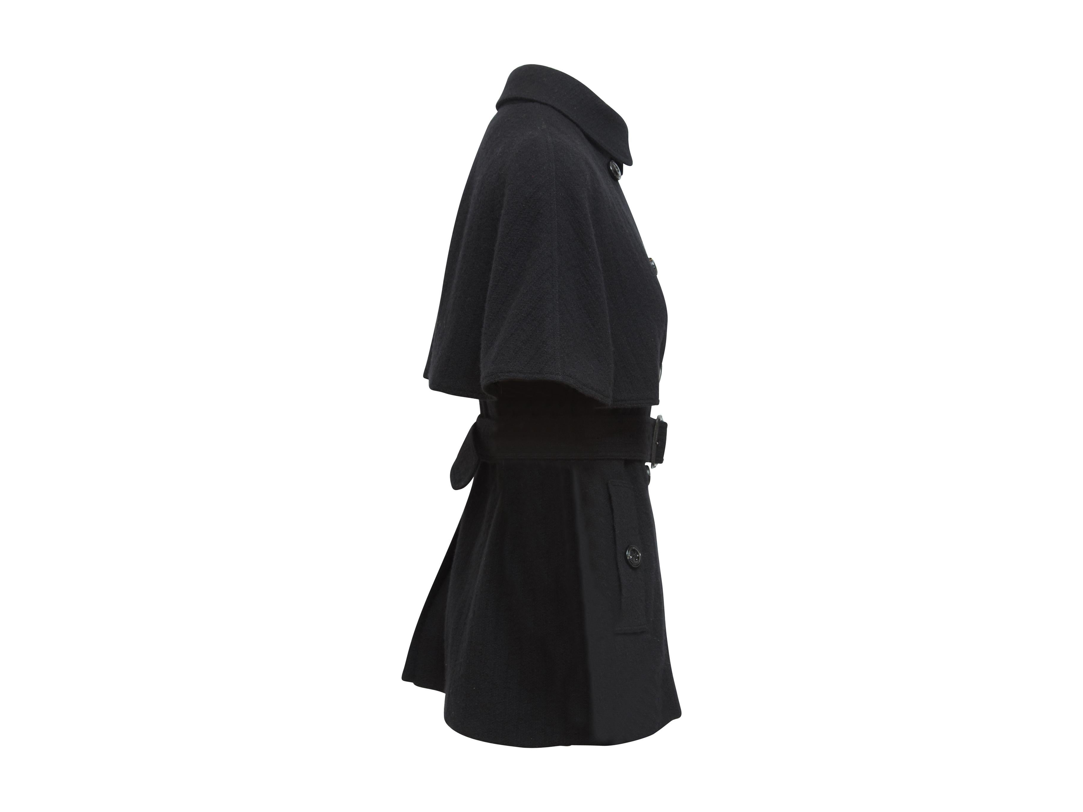 Product details:  Black coat with cape by Burberry London.  Rounded point collar.  Double-breasted button-front closure.  Adjustable belted waist.  Waist button slide pockets.  Cape secured by back button.  Center back hem vent.  30