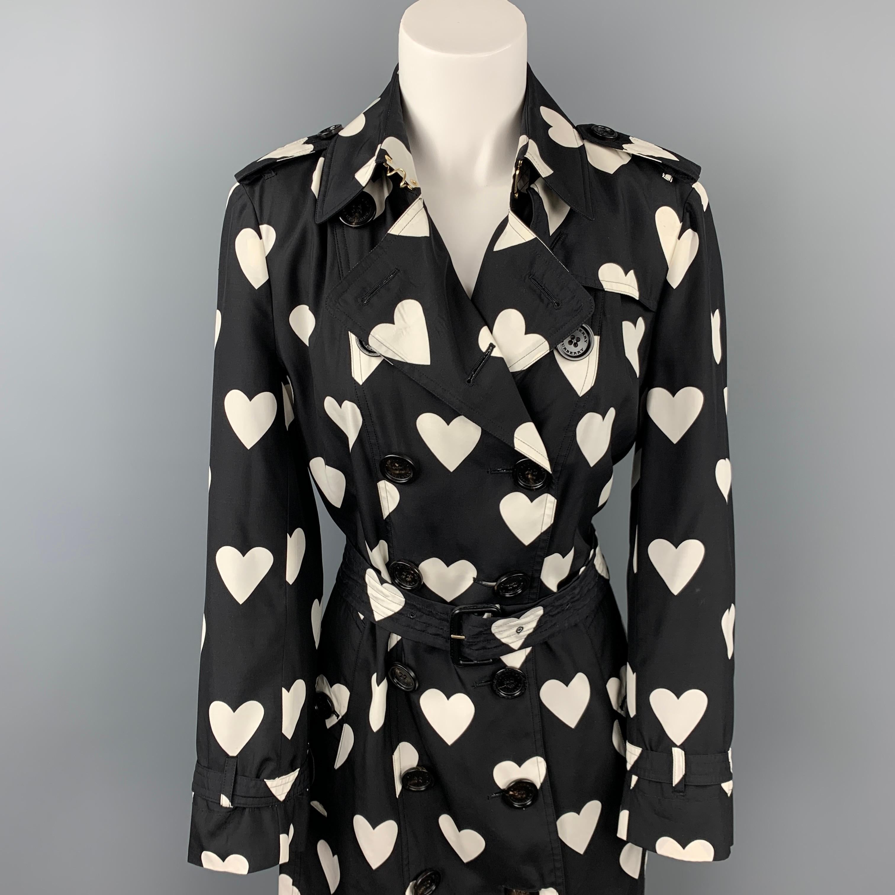 BURBERRY LONDON trench coat comes in a black & white heart print silk / wool with a full liner featuring a belted style, epaulettes, buttoned pockets, hook & loop collar detail, and a double breasted closure. Made in Poland. 

Very Good Pre-Owned