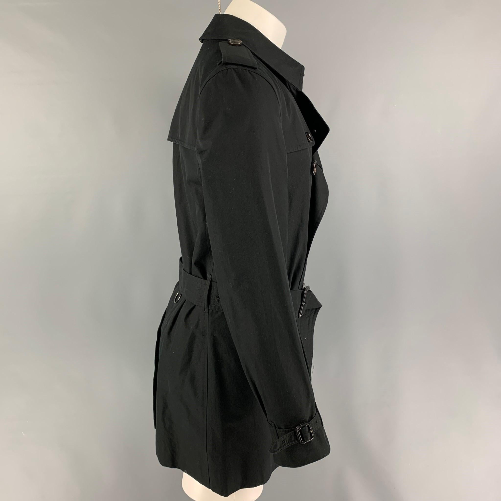 BURBERRY LONDON coat comes in a black cotton with a full plaid liner featuring a belted detail, epaulettes, slit pockets, and a double breasted closure. Includes dust bag. 

Very Good Pre-Owned Condition.
Marked: 50

Measurements:

Shoulder: 17.5