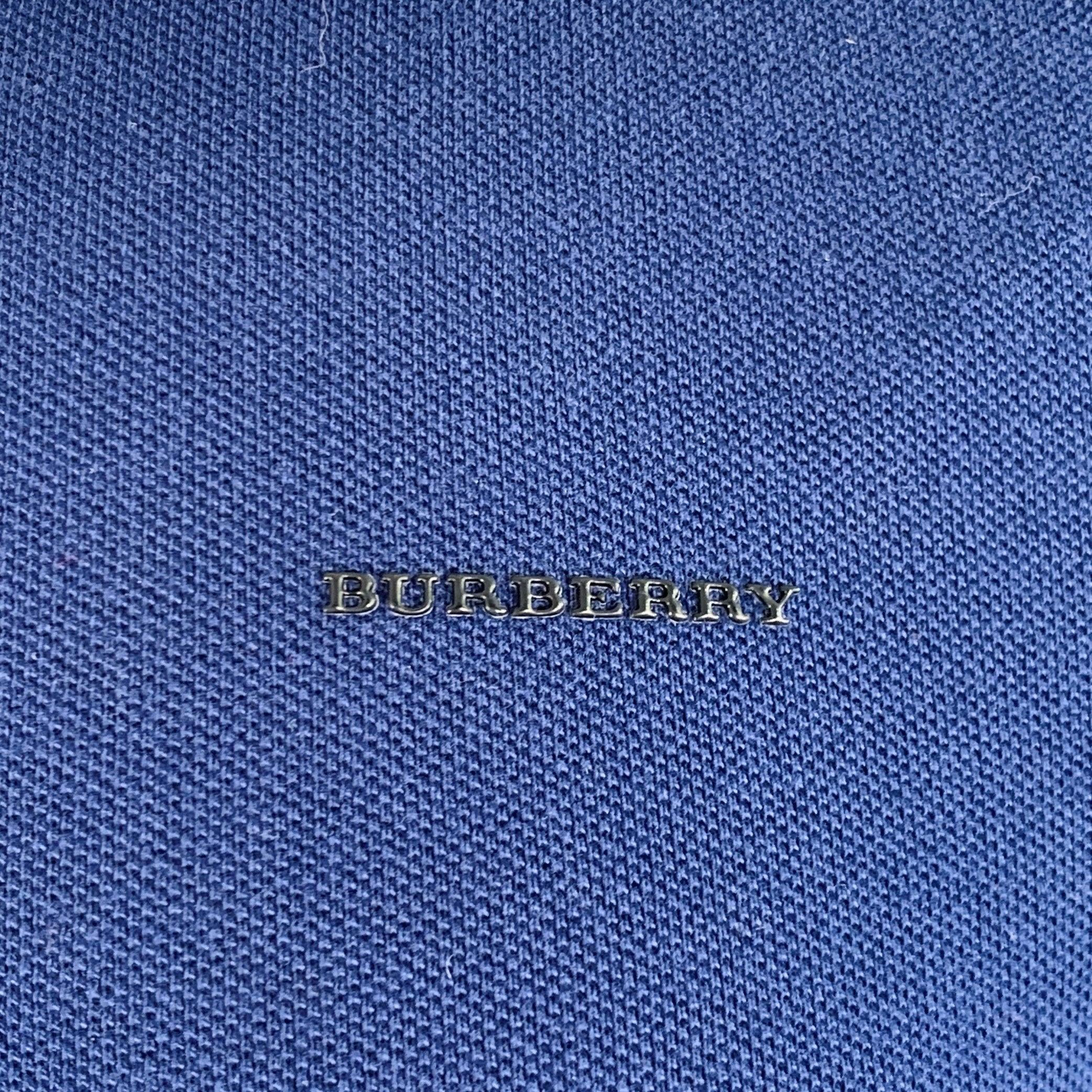 Polo Burberry London
in piqué di cotone blu con colletto a righe verde oliva a contrasto, maniche corte e mezza abbottonatura. Made in Portugal.Eccellente condizione di usato. 

Contrassegnato:   M 

Misure: 
 
Spalla: 16 pollici Petto: 39 pollici