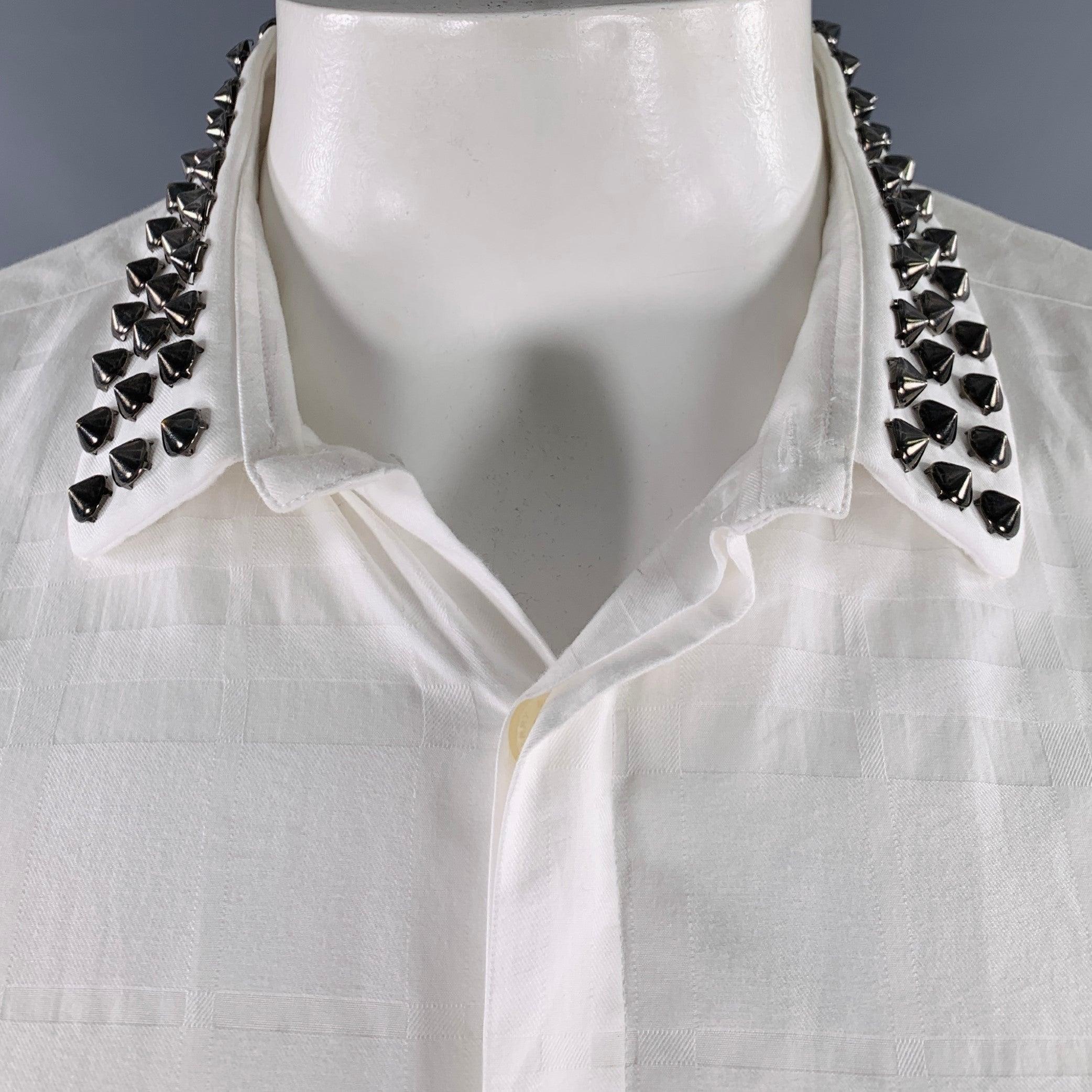 Camicia a maniche lunghe Burberry London
in cotone bianco con sottile motivo a quadri, colletto con borchie e chiusura con bottoni nascosti. È stato riparato sul lato inferiore sinistro della camicia, manca una borchia, così com'è. 

Contrassegnato:
