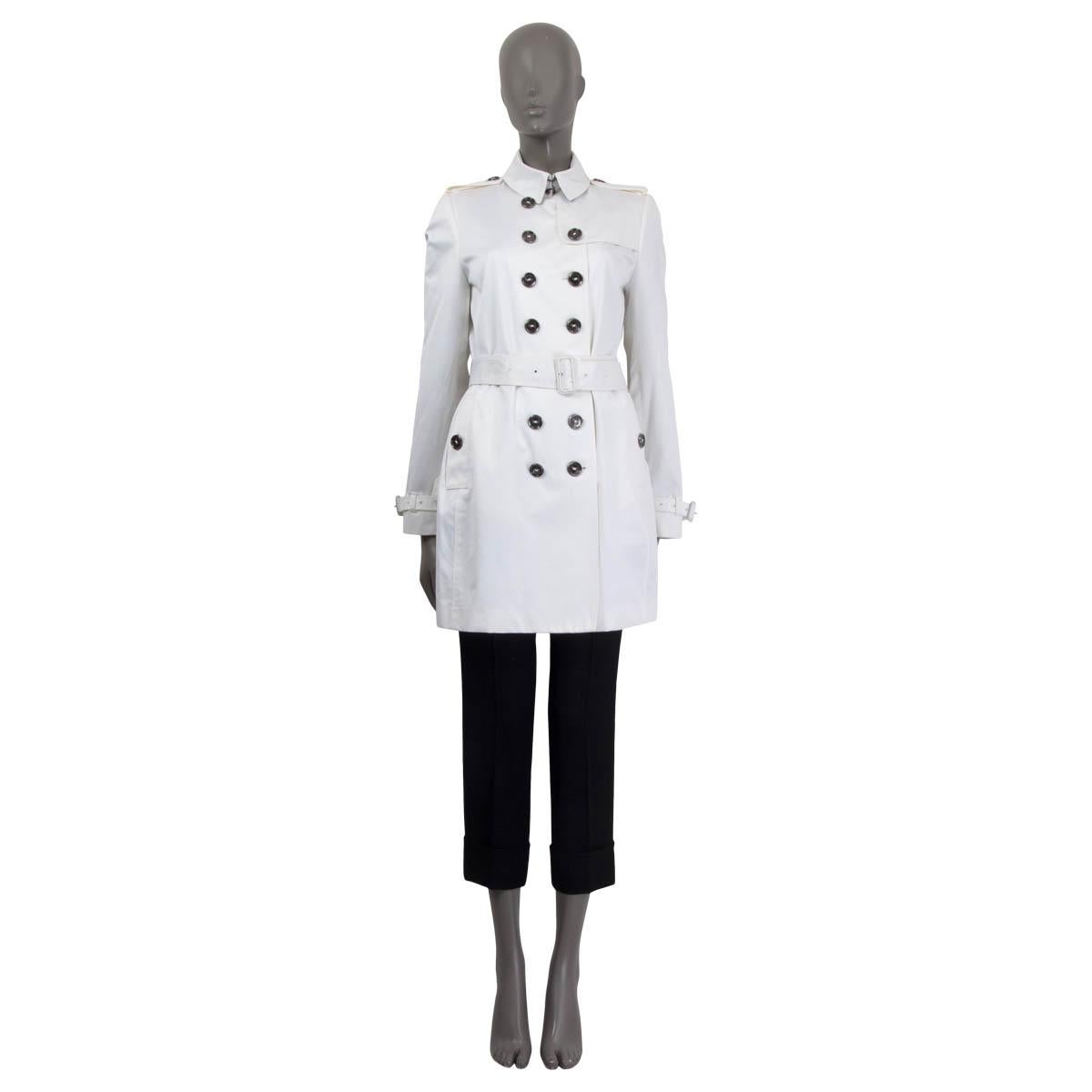 100% authentic Burberry London double-breasted short trench coat in white cotton (99%) and elastane (1%) with belted cuffs and shoulder epaulets. Closes with one hook at the neck, seven buttons on the front and a belt at the waist-line. Lined in