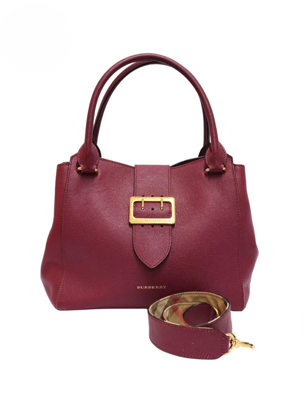 Burberry Medium Maroon Buckle Tote, Features Large Gold Buckle, Magnetic Closure, Removable Strap and Three Interior Pockets.

Material: Leather
Hardware: Gold
Height: 29cm
Width: 29.5cm
Depth: 9.5cm
Handle Drop: 18cm
Overall condition: