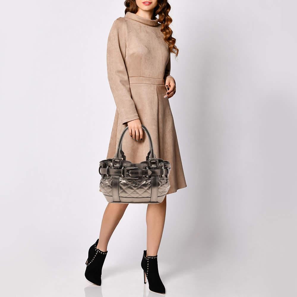 Crafted from quilted leather, this Burberry Beaton bag is detailed with a fashionable belt buckle, Burberry's equestrian knight logo, and double leather handles. The easy-to-organize interior is lined with nylon and features a zip pocket.
