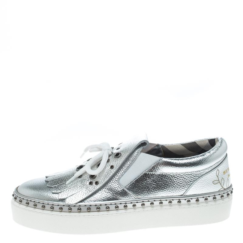 Shimmer away in comfort and style with this pair of sneakers by Burberry. They've been crafted from metallic silver leather and styled with ties and fringe details on the uppers. Studs and platforms beautifully complete the sneakers.

Includes: