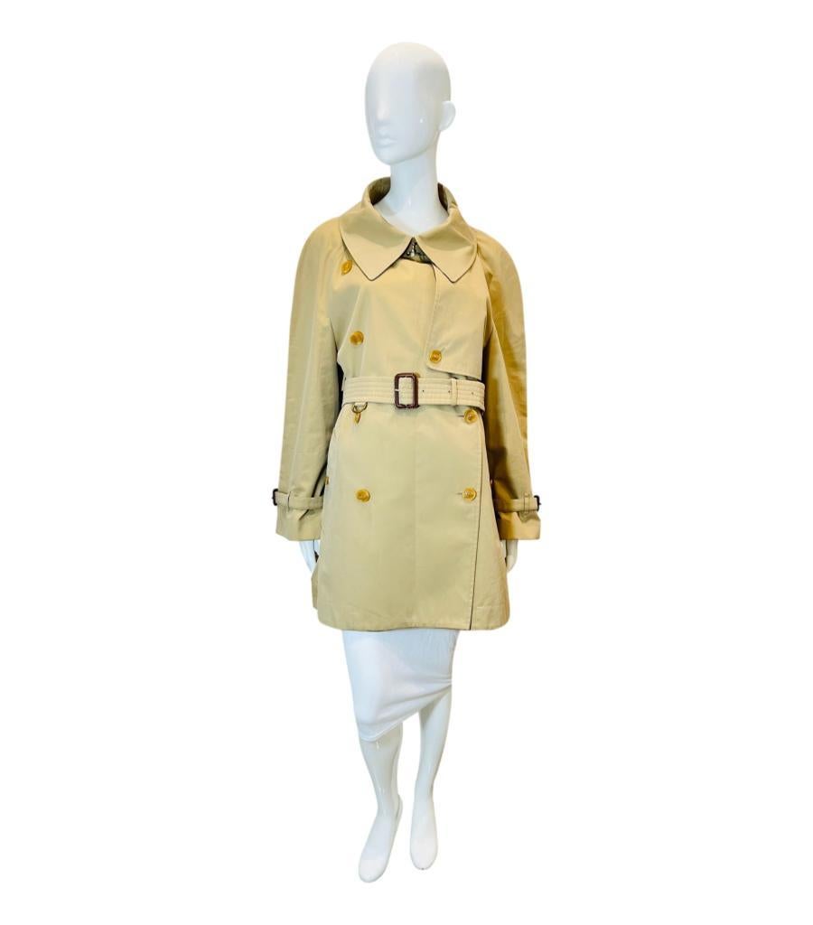 Burberry Mid Length Cotton Trench Coat
Iconic double-breasted beige trench coat designed with resin 'Burberry' engraved buttons.
Featuring brown leather buckled belted waist and cuffs, storm shield to rear.
Size – 14UK 
Condition – Very