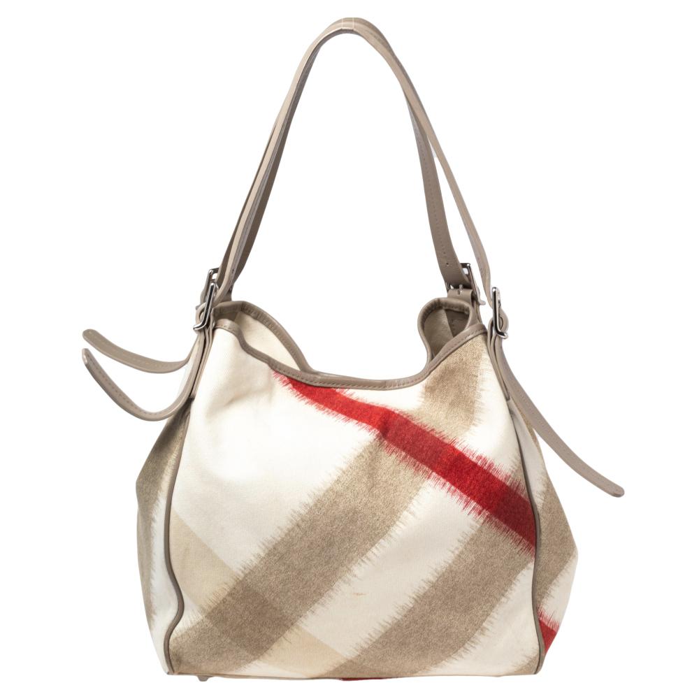 This classic tote by Burberry has a signature look. Crafted fabulously, this bag is made of the brand's Ikat check canvas and has leather trims. The bag is held by dual handles and opens to reveal a spacious canvas-lined interior. It is a great