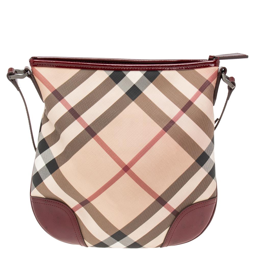 This stylish crossbody bag from Burberry has been crafted from PVC in signature Nova Check and accented with patent leather trims. The zip-top closure opens to a spacious fabric-lined interior. The bag comes with a shoulder strap and is perfect for