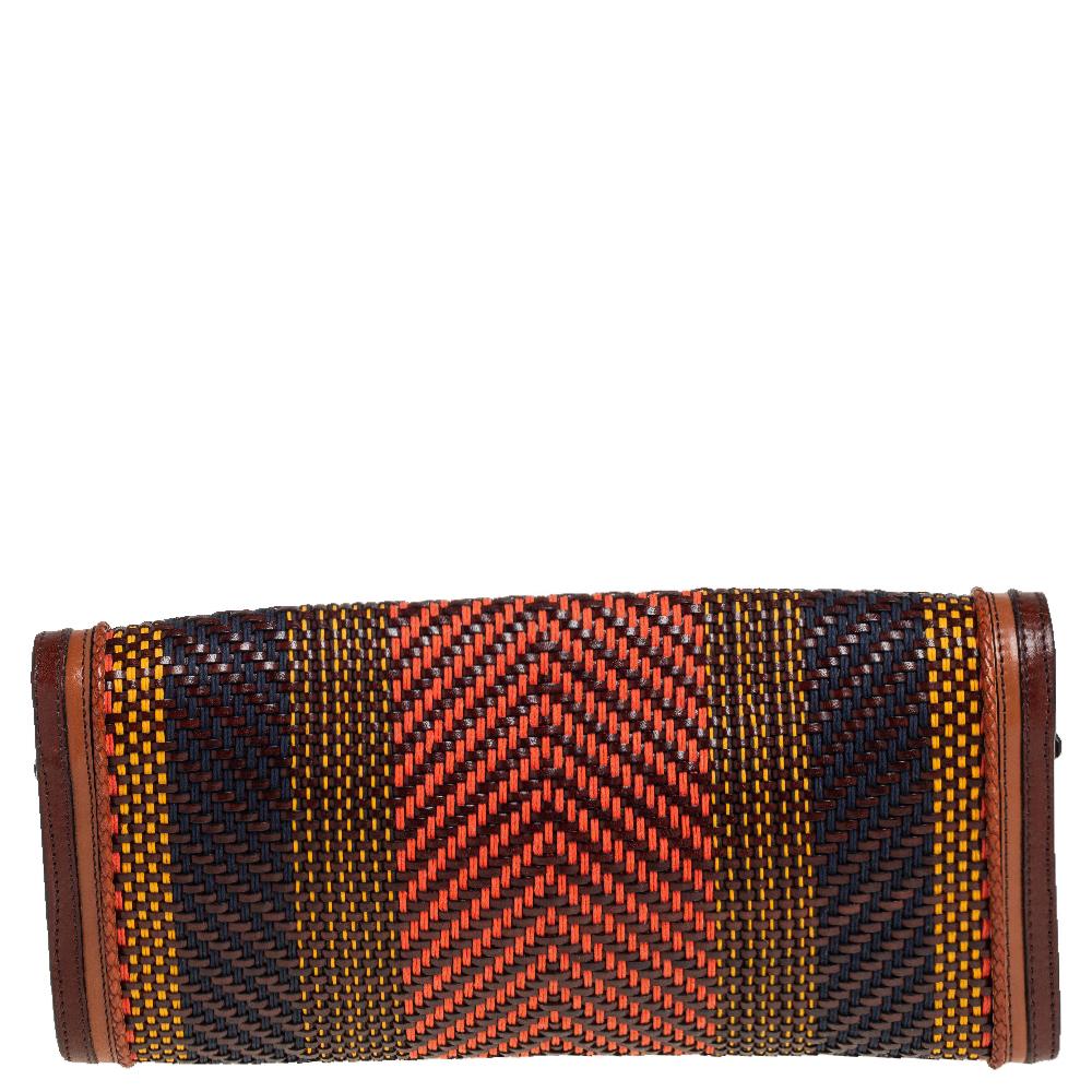 This clutch by Burberry is a creation that is not only stylish but also exceptionally well-made. Meticulously woven from leather, the multicolored exterior is stunning and equipped with a flap adorned with buckles. The flap opens and leaders the way