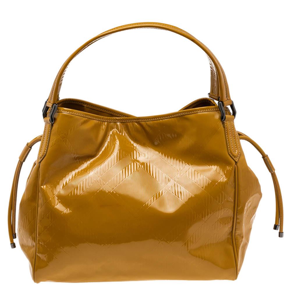 You'll get the best of fashion and function when you choose this Bilmore tote by Burberry. It has been crafted from glossy, mustard patent leather. The bag has a spacious canvas interior capable of holding all your essentials and is complete with