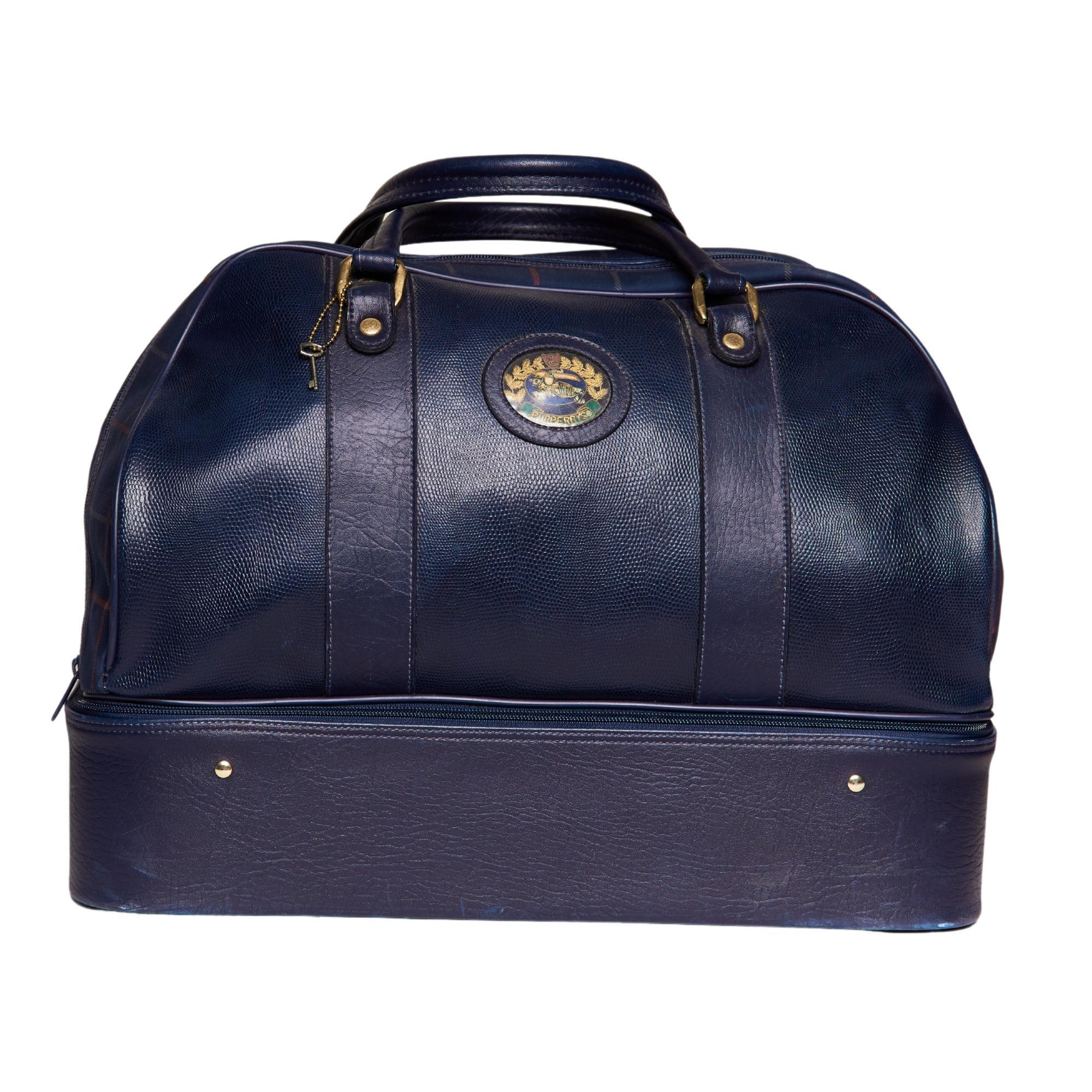 COLOR: Navy
MATERIAL: Leather and cloth
MEASURES: H 15” x L 20” x D 11”
DROP: 7”
COMES WITH: Attached lock onside and key
CONDITION: Good - scratches to leather throughout, rub marks scuffing to corners, faint scratches to hardware, and small scuffs