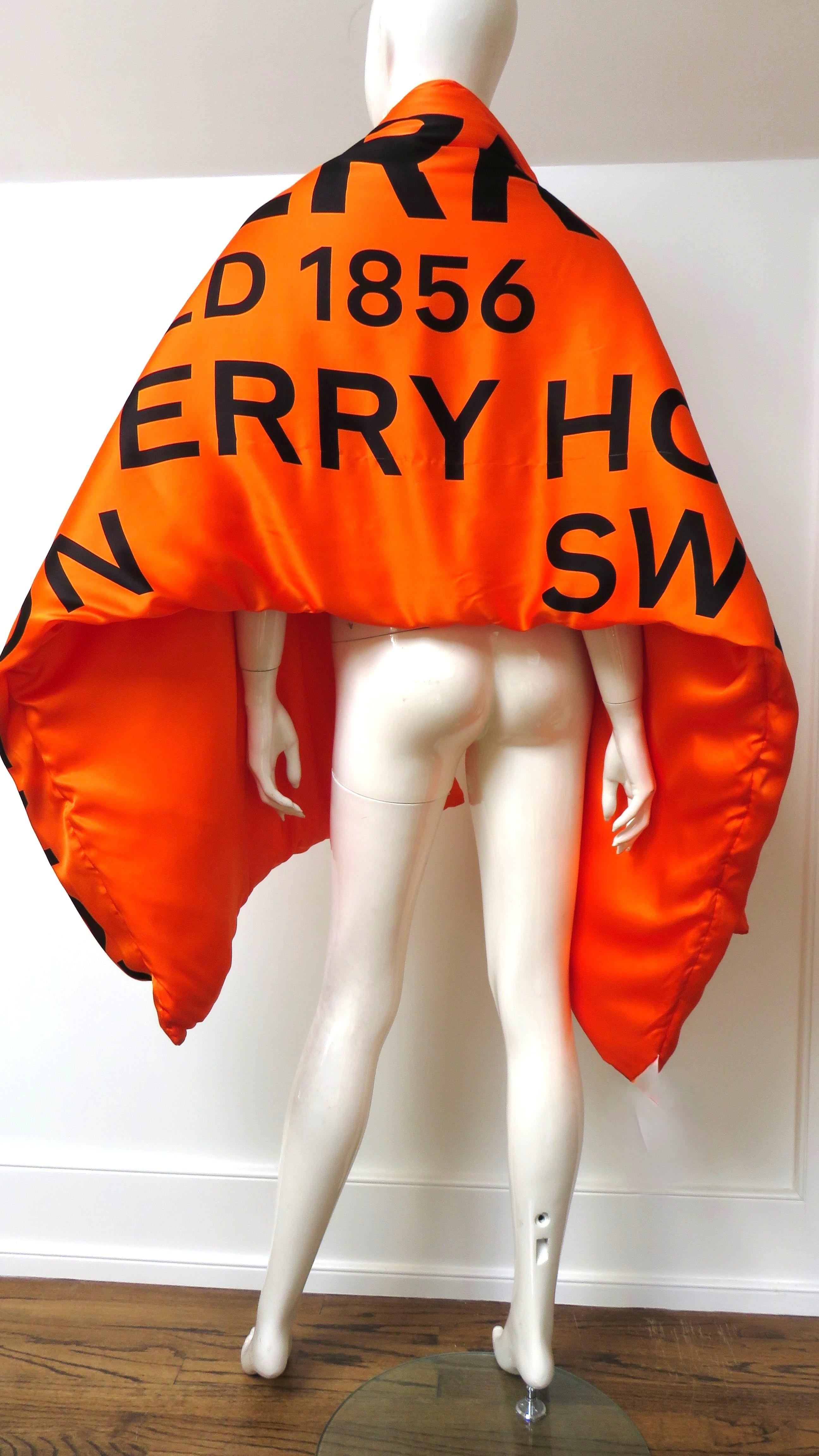 Una splendida fascia, sciarpa e scialle di colore arancione brillante con scritte nere raffiguranti il logo Burberry e l'anno di fondazione dell'azienda a Londra sul davanti, arancione pieno sotto. Ci sono diverse rotture che non si notano sulla