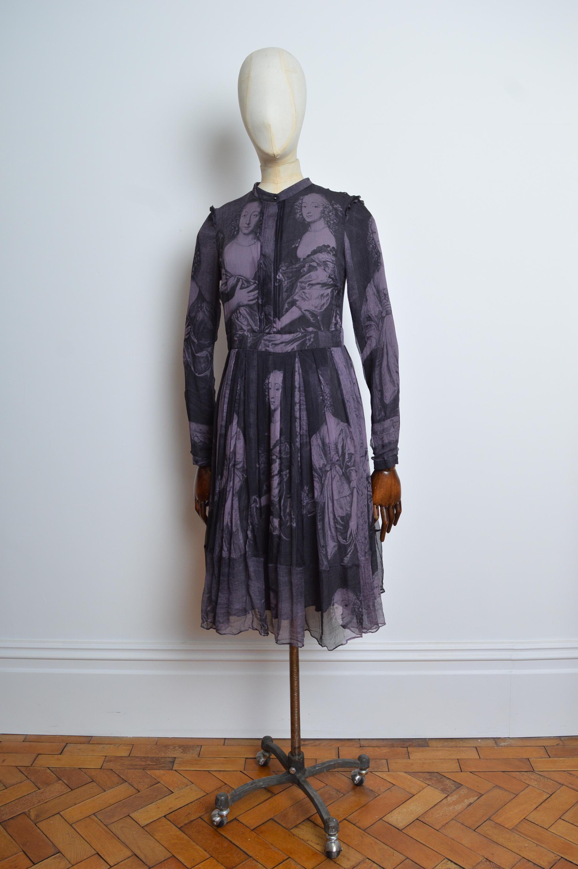 Abito decorato in pura seta di Riccardo Tisci per Burberry in chiffon nero e lilla scuro con maniche lunghe, bottoni sul davanti, incredibile stampa di quadri antichi, zip laterale nascosta e orlo al ginocchio. 
Taglia: EU42 (consigliamo di