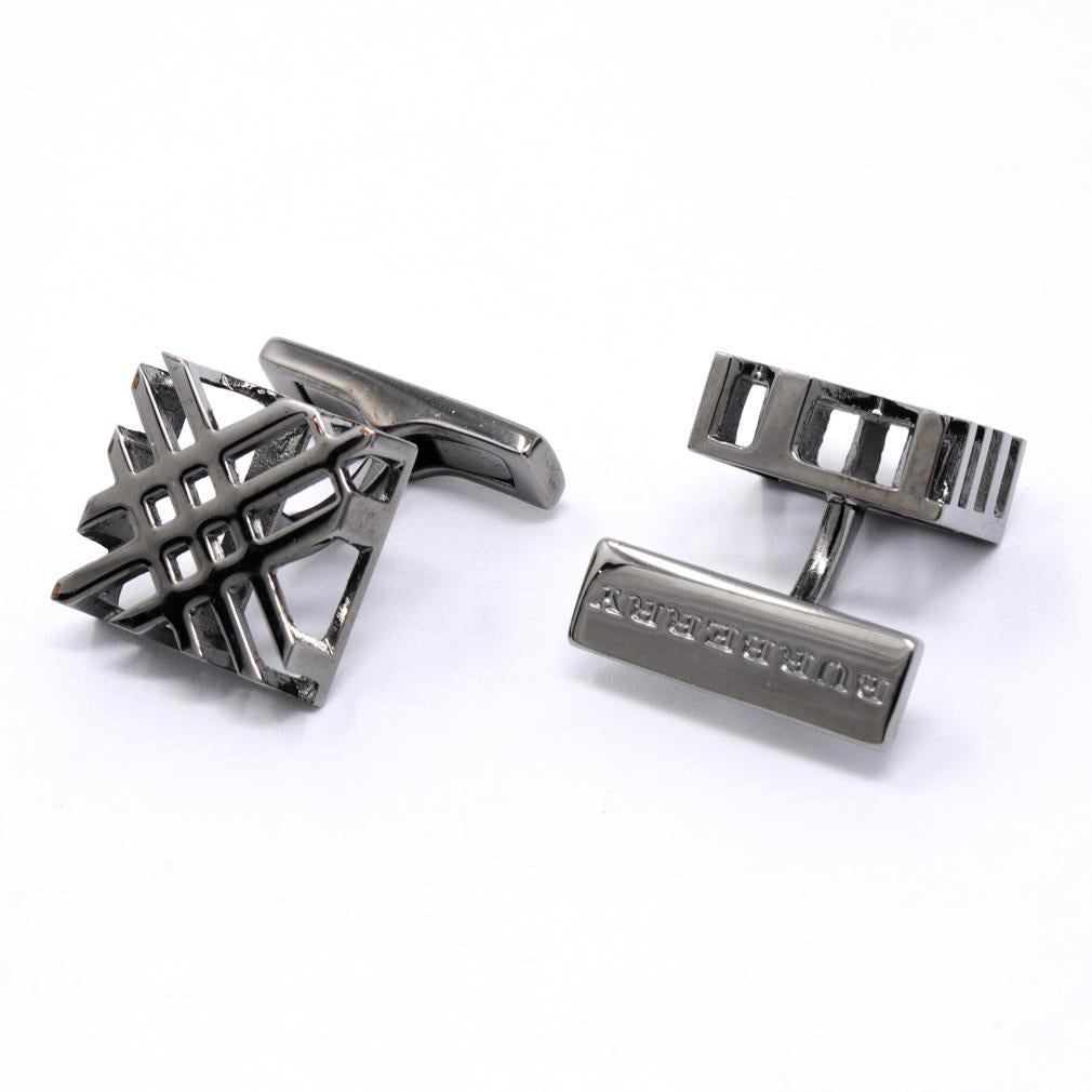 Burberry Openwork Nova Check Cufflinks. Cast from a dark silver tone metal. The Burberry Nova Check is rendered in a square format on the diagonal and hollow underneath with a curved post and a whale back swivel stamped “BURBERRY”
Condition: