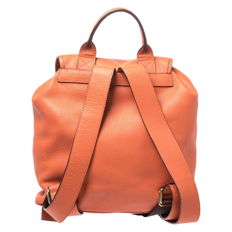 This stunning creation comes from the iconic house of Burberry. Designed to deliver style and functionality, it is a closet must-have. Crafted in Italy, it is made from quality leather and flaunts a lovely shade of orange. It features a top handle,