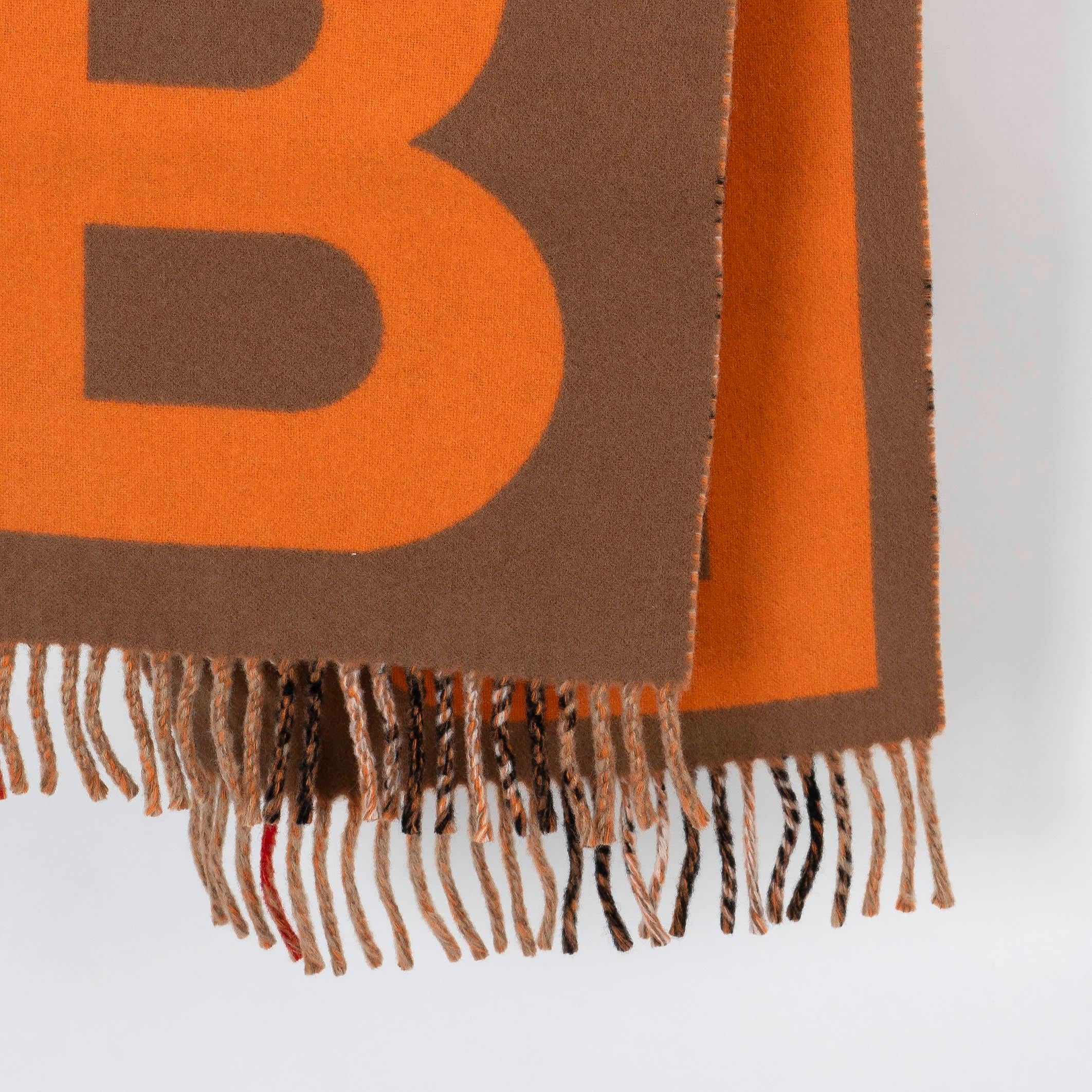 This 100% authentic Burberry TB Diamonto Giant Check muffler is crafted from a luxurious cashmere-wool blendin a striking palette of orange, brown, beige, black, white, and red. The iconic Giant Check pattern is complemented by the signature TB