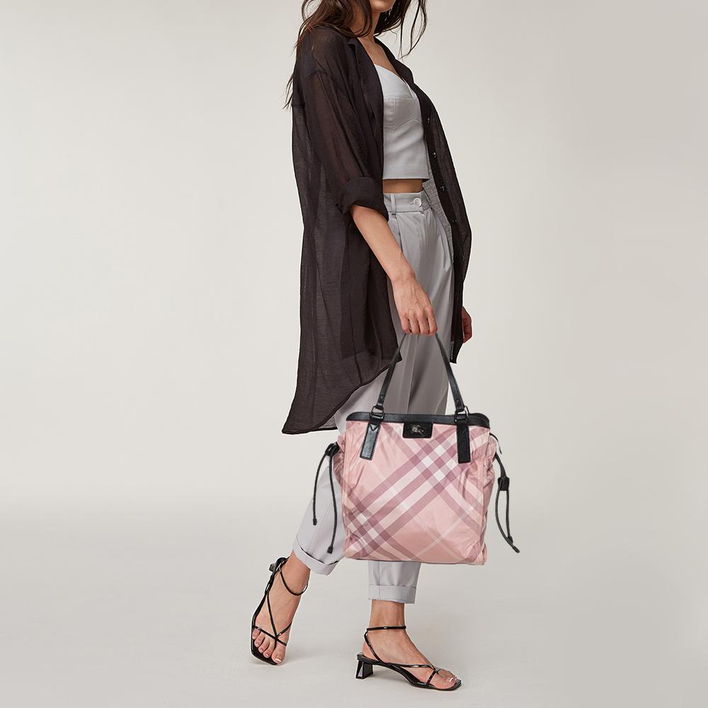 This classy and praiseworthy Buckleigh tote coming from Burberry is a must have. It is crafted from signature checked nylon and leather, featuring dual top flat handles. This tote reveals a nylon-lined interior with a zip pocket along with brand