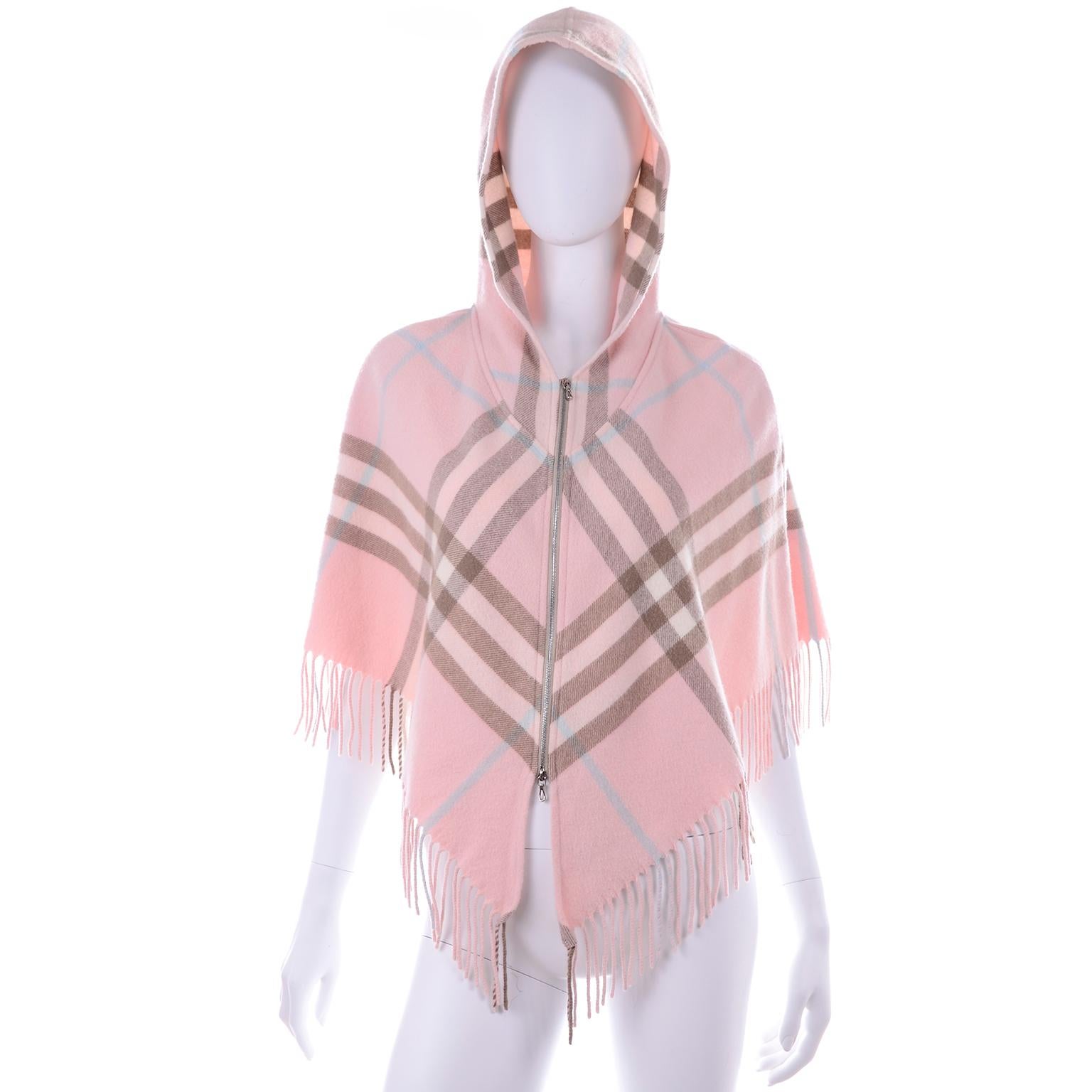 This is a pretty Pink Plaid Burberry poncho with a hood. Cropped style so can fit up to a size Medium and it has a metal zipper down the center front with a bottom zipper that can be worn open from the bottom.  Made in Scotland. of 90% Merino Wool