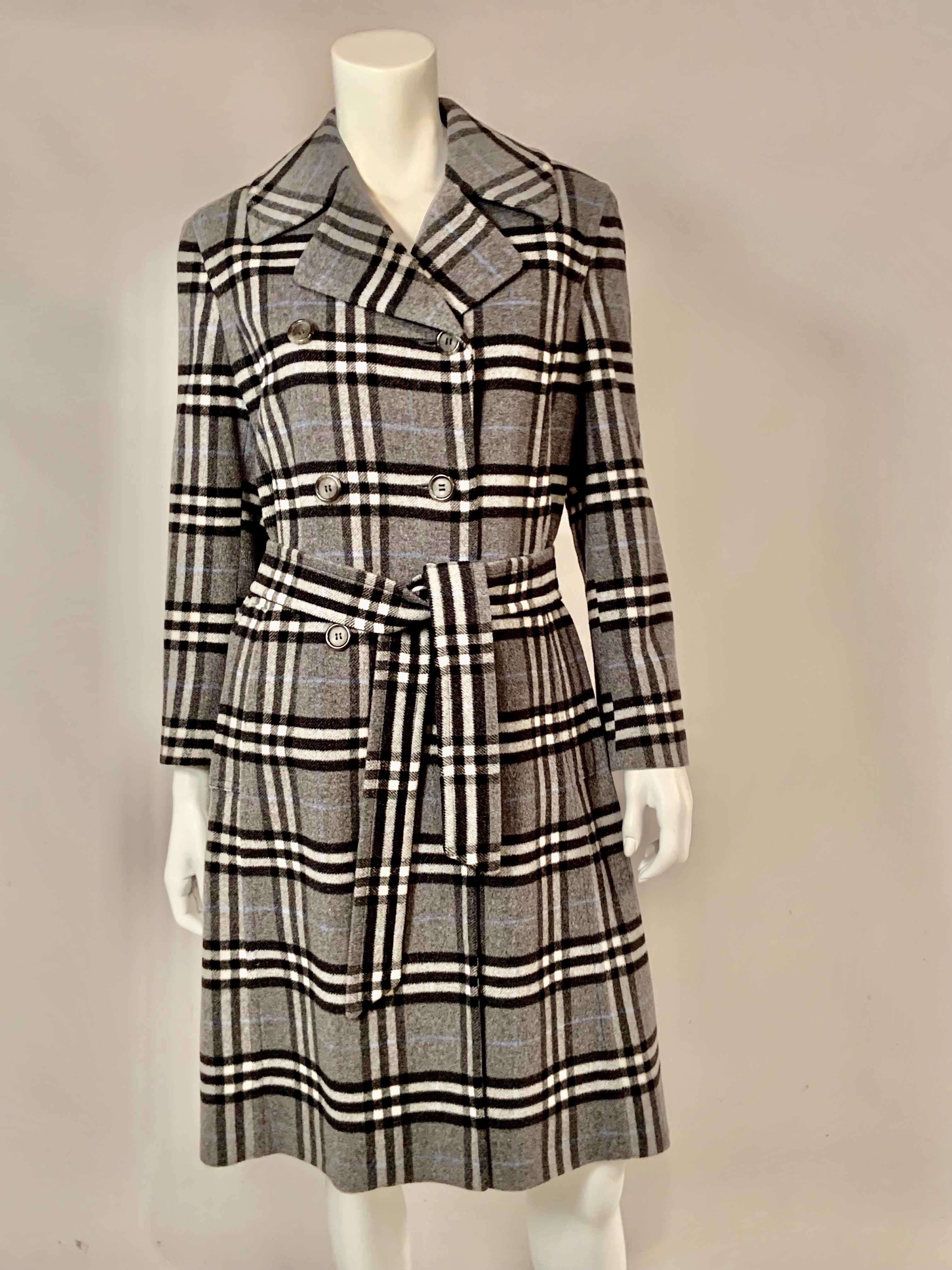 This classic Burberry London double breasted cashmere and wool blend coat looks as if it has never been worn. It is in pristine condition.  The grey plaid is accented with black, white and light blue.  The coat has notched lapels, two pockets and a