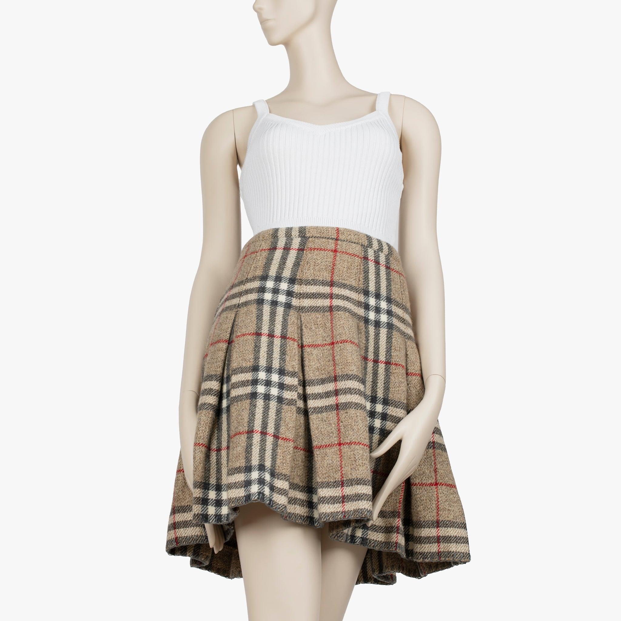 L'heritage check di Burberry è immediatamente riconoscibile e questa gonna a pieghe in lana cattura l'intramontabile eleganza britannica della casa. Realizzata in lana beige con accenti plaid neri, bianchi e rossi, la gonna è tagliata in modo da