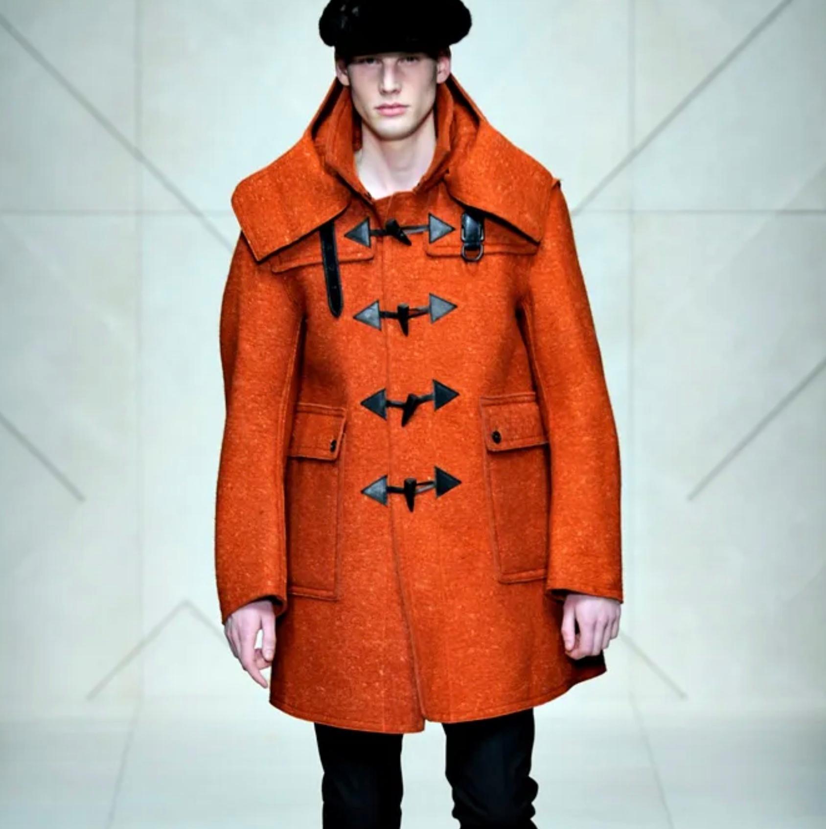 BURBERRY PRORSUM Fall-Winter 2011 coat comes in a orange heather wool featuring a detachable hood, leather trim, collar strap, front pockets, back belt, hook & loop detail, and a toggle closure. Made in Italy.

Very Good Pre-Owned Condition.
Marked: