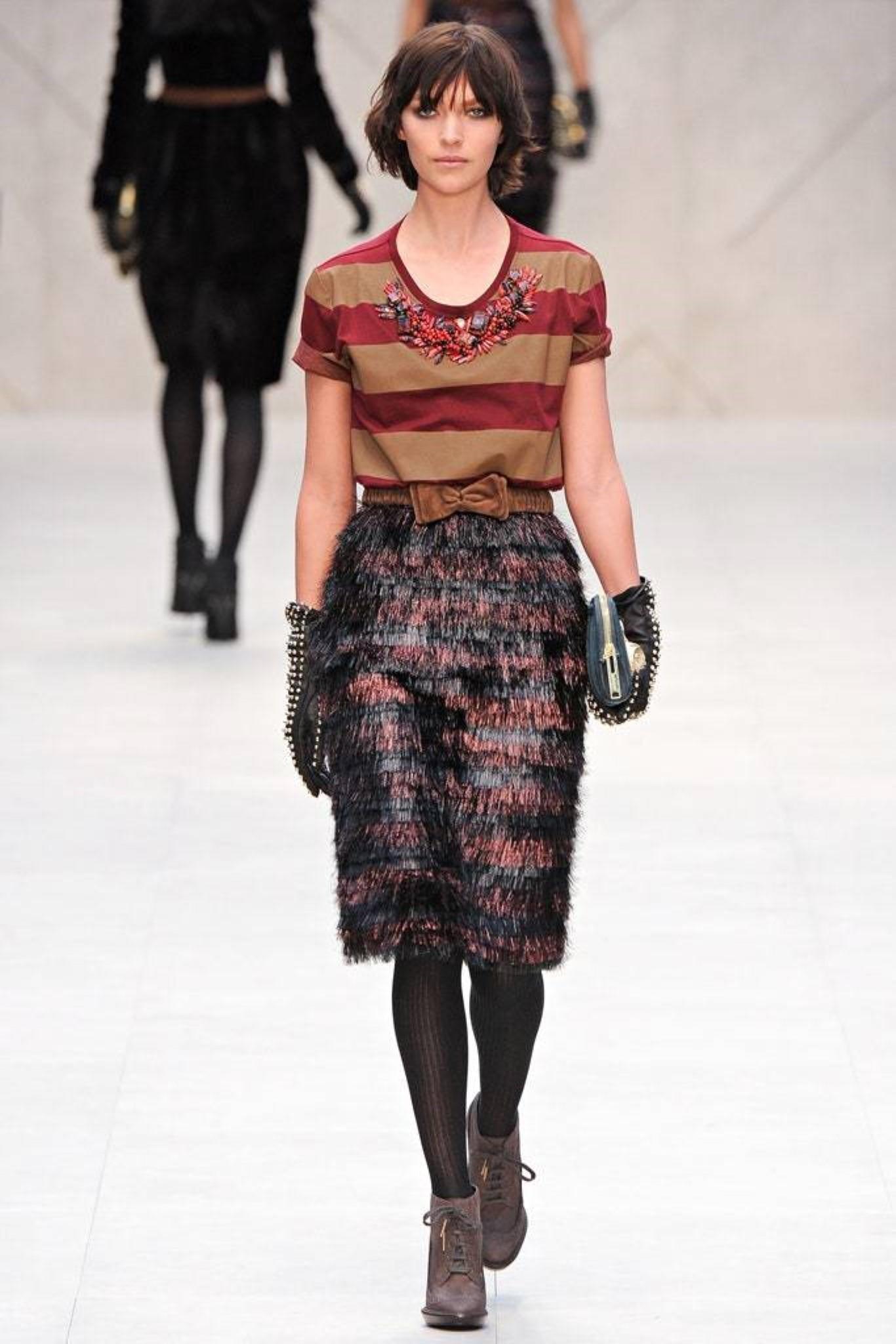 La gonna Burberry Prorsum Autunno 2012 è in poliammide/seta a righe color ciliegia e nero con fodera sottoveste, ha una vestibilità dritta, uno spacco posteriore e una chiusura posteriore con zip. Prodotto in Italia. 

Nuovo Tag Wit. 
Marcato: