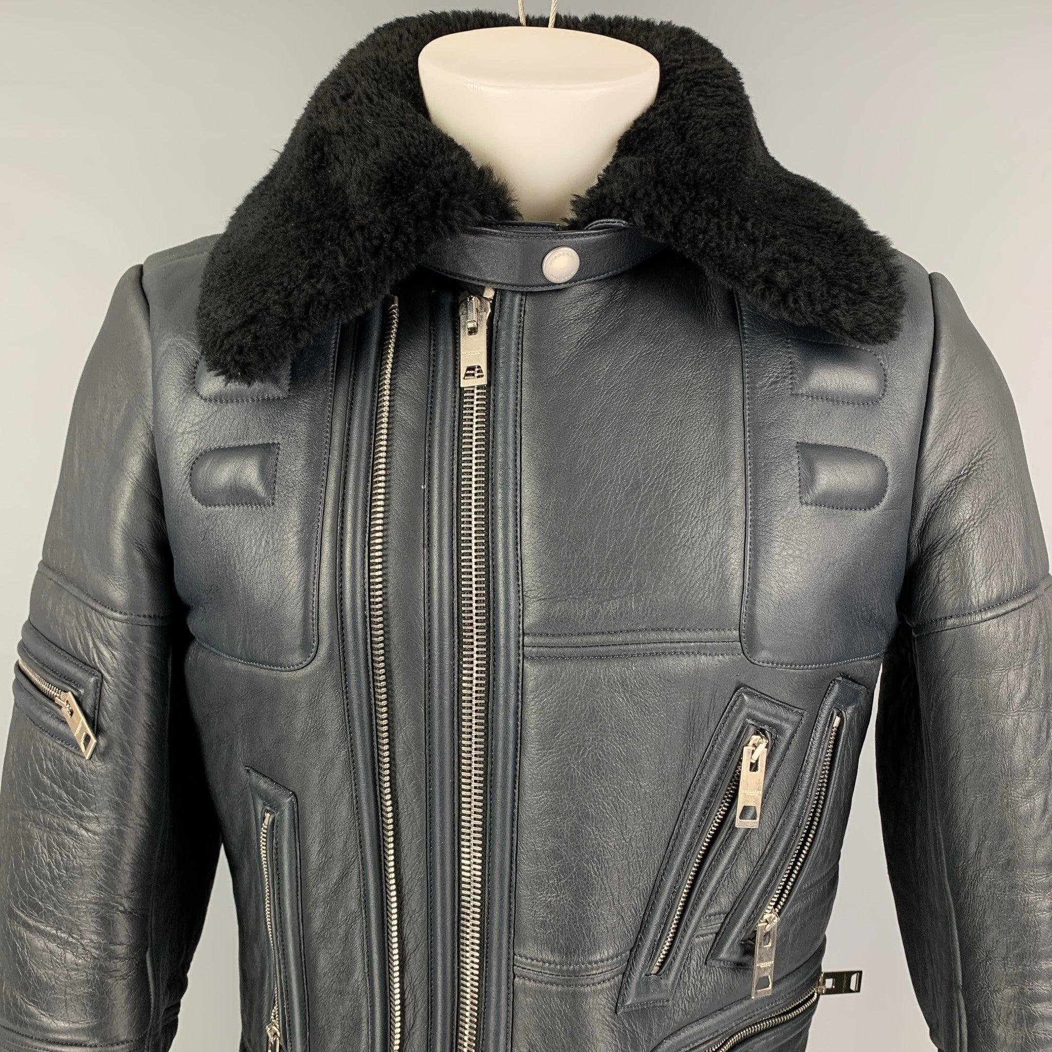 La veste PRORSUM FW 2010 de Burberry est réalisée en cuir d'agneau bleu foncé. Elle présente un style motard, un col en mouton noir, des détails paddés, des ferrures argentées, une ceinture, des poches zippées, des poignets zippés et une double
