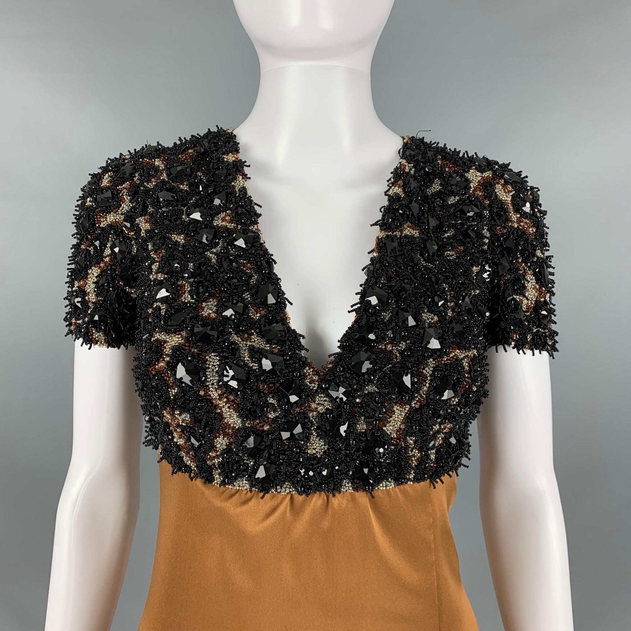 La robe du soir Pre-Fall 2013 de Burberry PRORSUM se présente dans une matière tissée en soie marron camel et présente une silhouette d'impératrice, des accents de perles et de cristaux, une fente sur le devant et une fermeture zippée au dos.