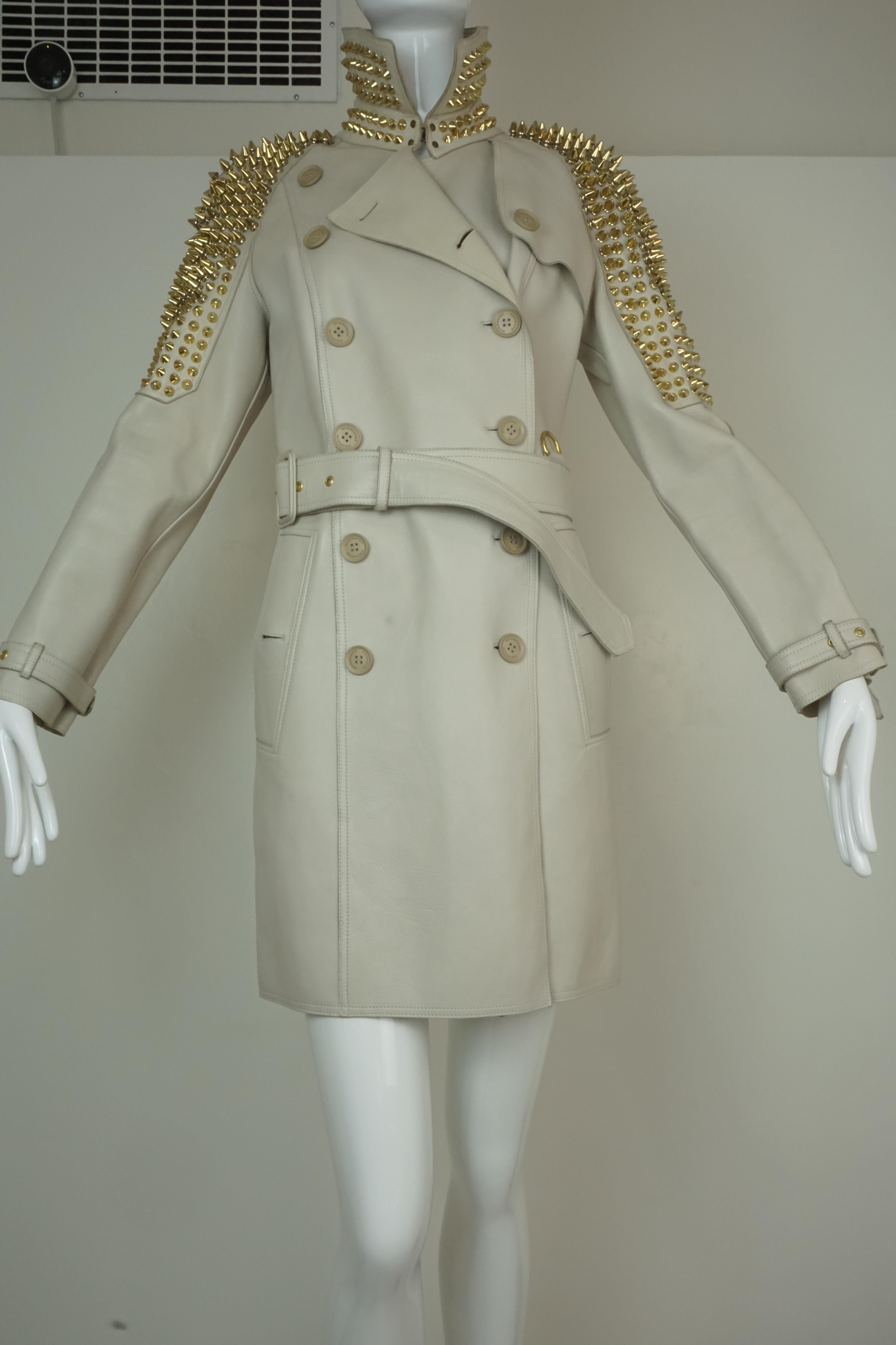 Burberry Prorsum belted trench coat in beige leather w/ gold spike punk rock studs on collar and sleeves. From Christopher Bailey's 2011 Biker collection. 

Foxy Couture is not an authorized reseller nor affiliated with any of the brands we
