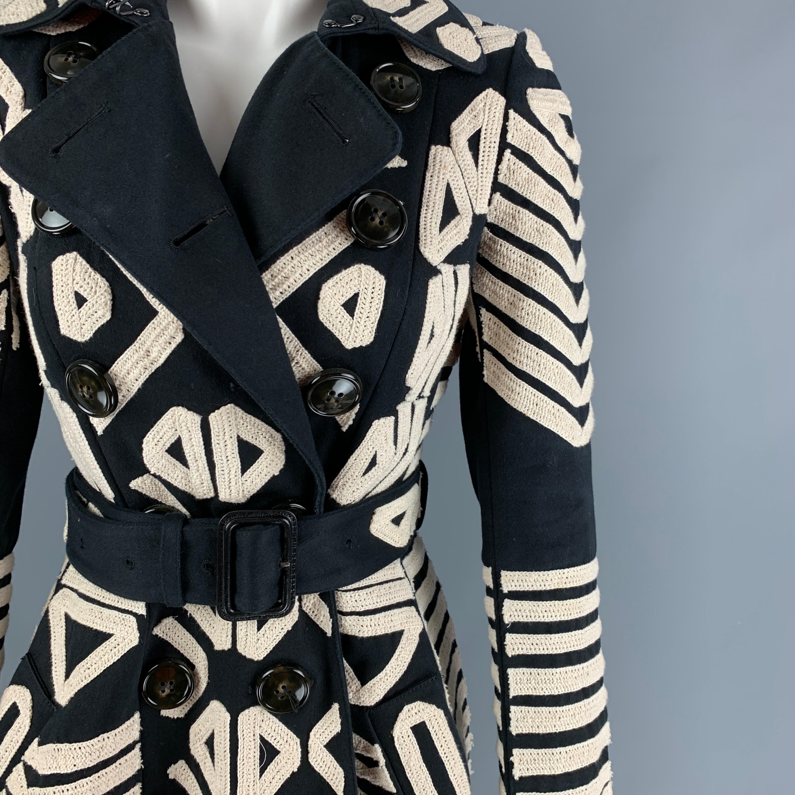 BURBERRY PRORSUM 2016 coat comes in a black & white cotton with embroidery designs throughout featuring a belted style, full liner, single back vent, slit pockets, and a double breasted closure. Made in Italy. 

Very Good Pre-Owned Condition. Light